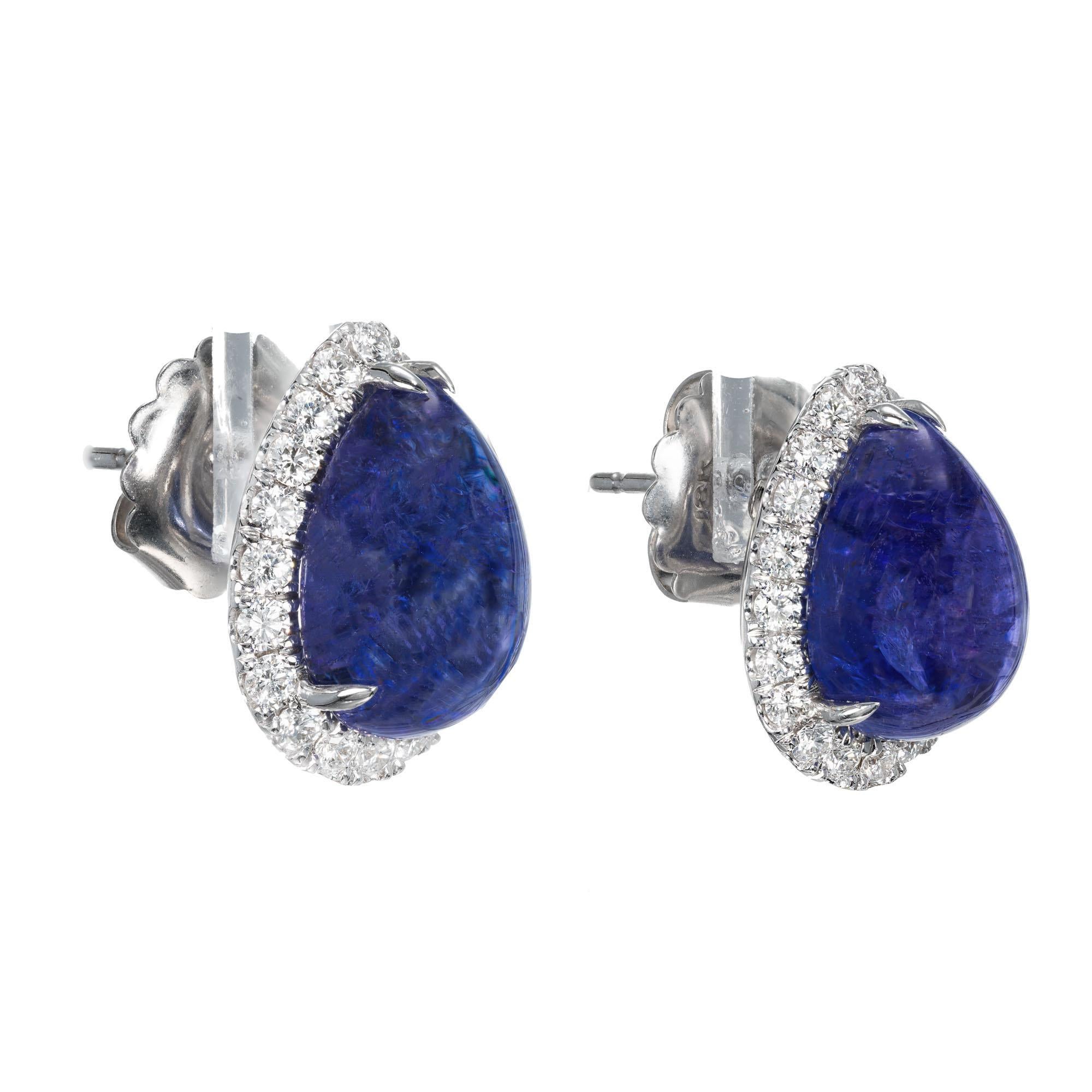 Two blue cabochon tanzanite in a handmade diamond halo 18k white gold earrings from the Peter Suchy Workshop.

2 pear shaped cabochon blue tanzanite, I approx. 13.70cts
40 round brilliant cut diamonds, F VS approx. .80cts
18k white gold 
Stamped: