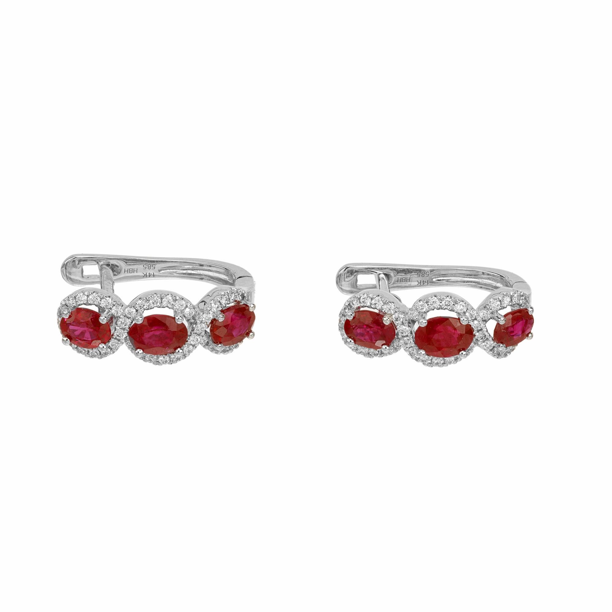 Peter Suchy oval ruby round diamond white gold hoop earrings. Crafted meticulously to mesmerize, these earrings each showcase three stunning oval ruby gemstones that are enriched by round brilliant cut diamond halos, in a frigure eight style. The