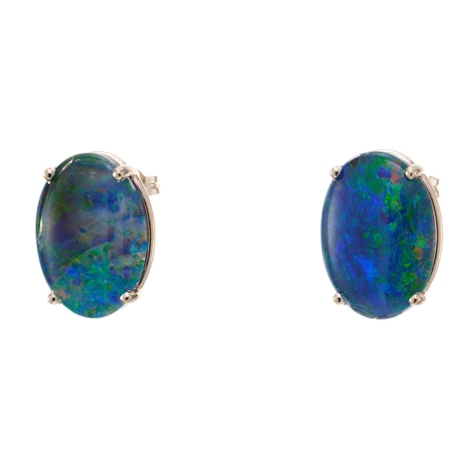 Oval opal earrings. Blue green oval triplets with red flash in 14k yellow gold four prong basket settings, with open work swirl gallery. Opal triplets are made with a slice of natural opal mounted on a  a black onyx base. The opal is covered by a