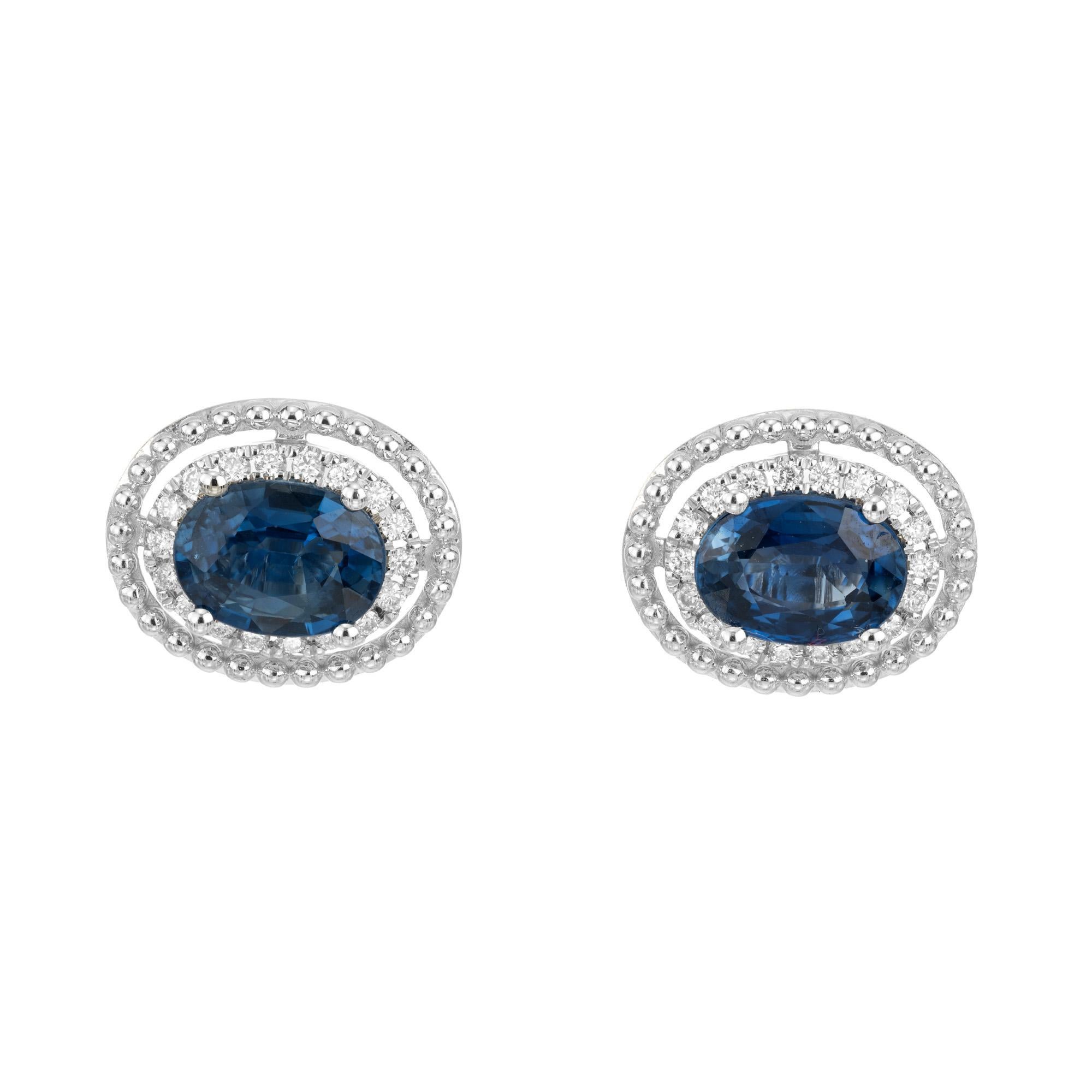 Bright blue natural sapphire and diamond stud earrings. 2 oval sapphires totaling 1.93cts mounted in 14k white gold settings accented 36 round brilliant cut diamonds in a halo style design. The second halo consists of a bead design. Designed and