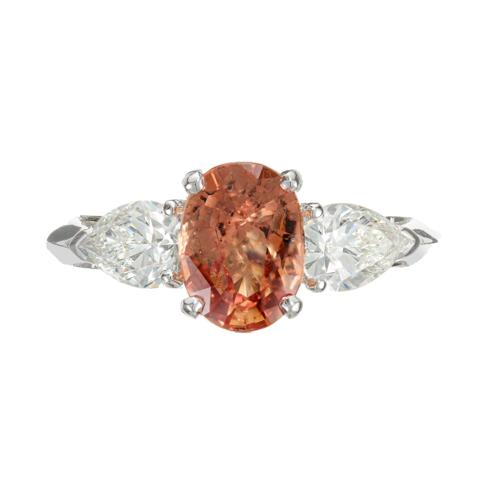 Bright natural untreated sapphire and diamond engagement ring. AGL certified, no enhancement 2.18 carat oval orange sapphire in a platinum three-stone setting with 2 GIA certified pear shaped diamonds. Strong orange color with a unique hint of pink.