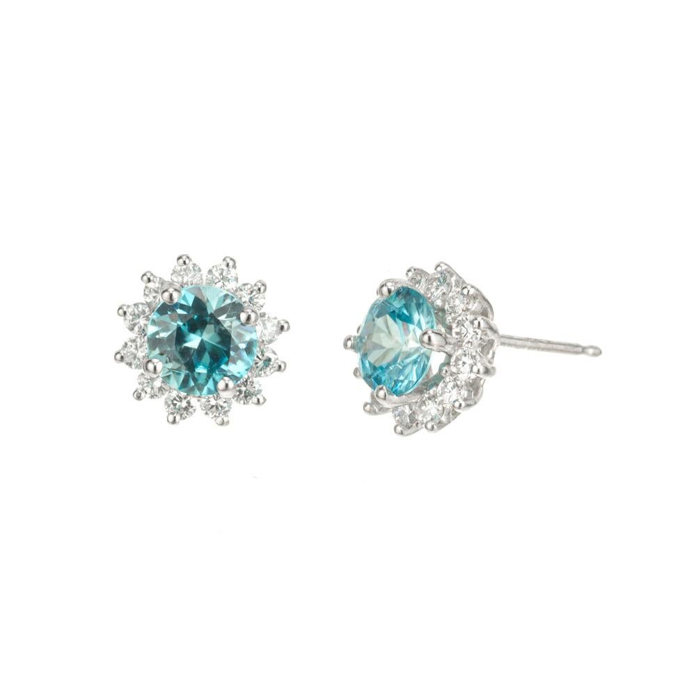 Blue zircon and diamond earrings.  Two 2.26 carat zircons each with a halo of 12 white round brilliant cut diamonds in 14k white gold settings. Designed and crafted in the Peter Suchy Workshop.
2 round blue zircon, approx. 2.26cts
24 round brilliant