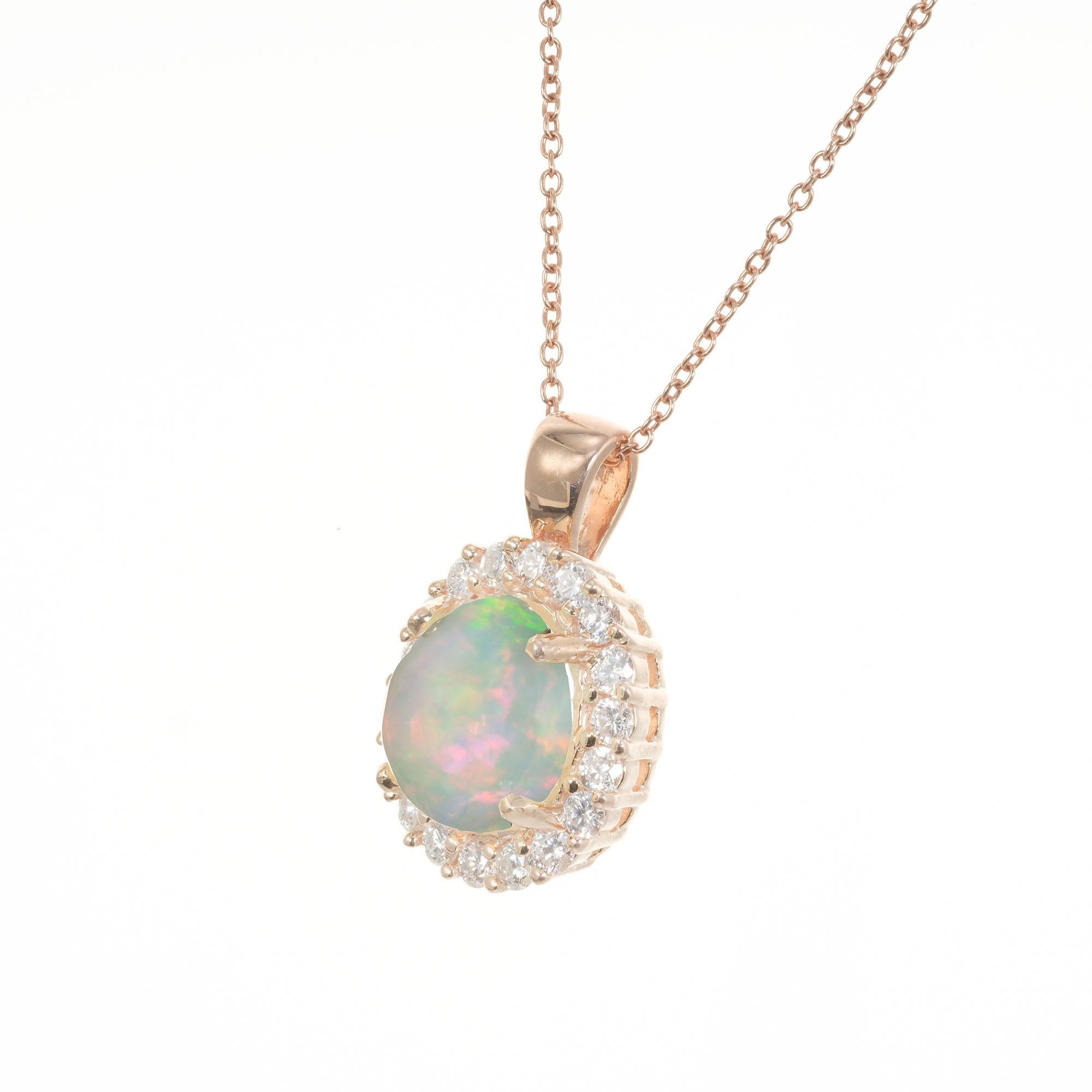 Opal and diamond pendant necklace. Oval cabochon center opal with a halo of 18 round brilliant cut diamonds in 14k rose gold. 18.5 inch chain. Red, blue and green translucent Opal. Created in the Peter Suchy Workshop. 

1 oval cabochon reddish