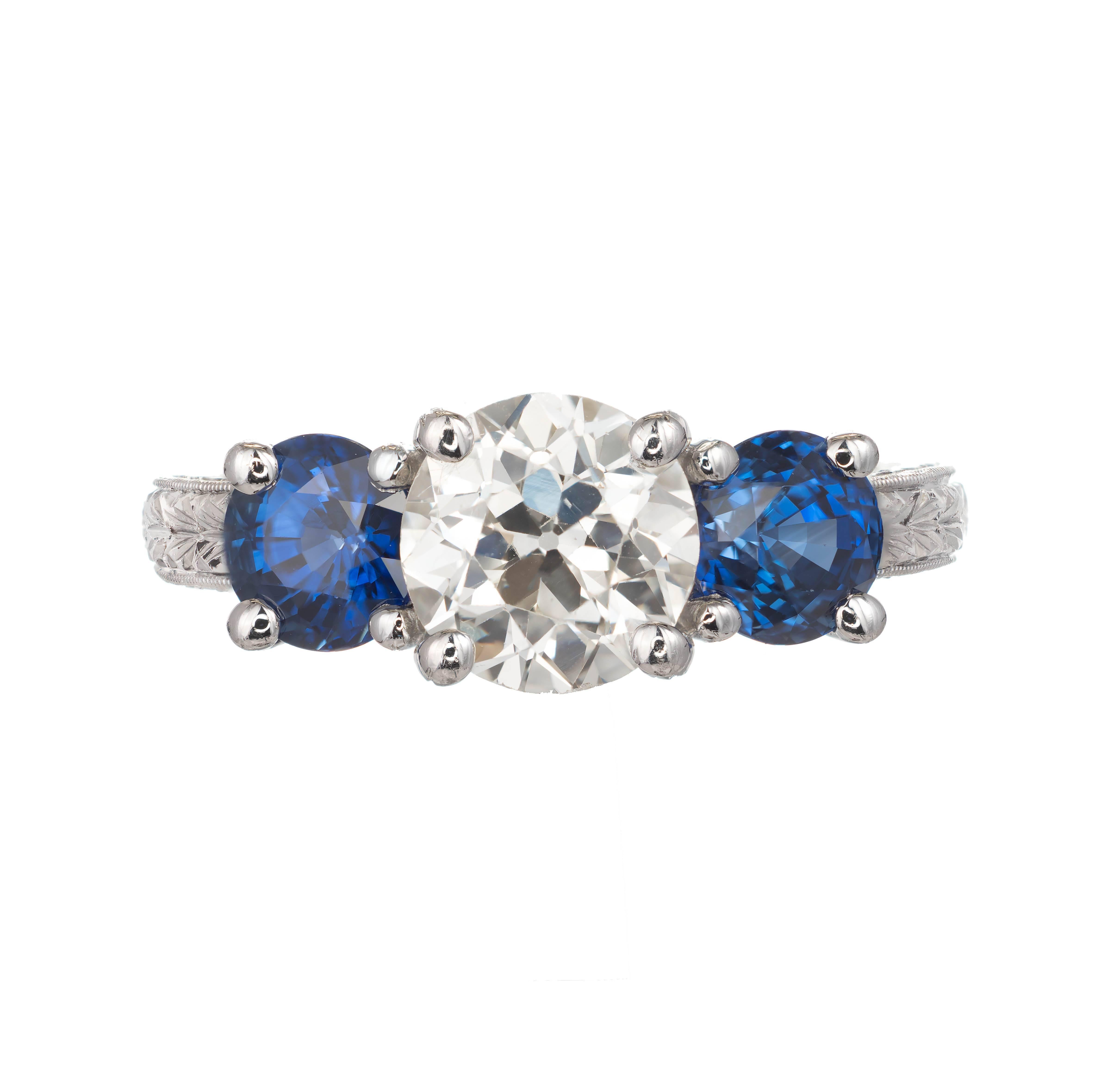 Peter Suchy diamond and sapphire three-stone engagement ring. 1.50cts Original European cut diamond complete with a raised crown and small table, Certified by the EGL as Old European cut.  Set with 2 extremely bright vivid blue European cut