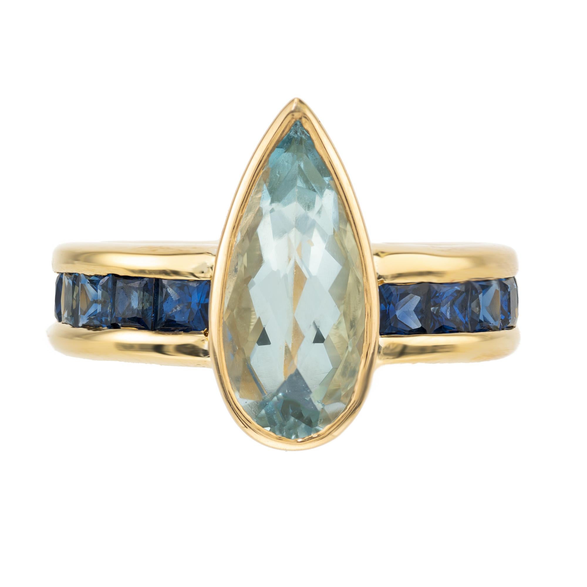 Exceptional natural untreated 3.19 carat pear shape aqua from an estate with a unique faceted top set in a custom 18k channel set ring with square blue sapphires. This beautiful ring truly showcases outstanding craftsmanship mixed with unique
