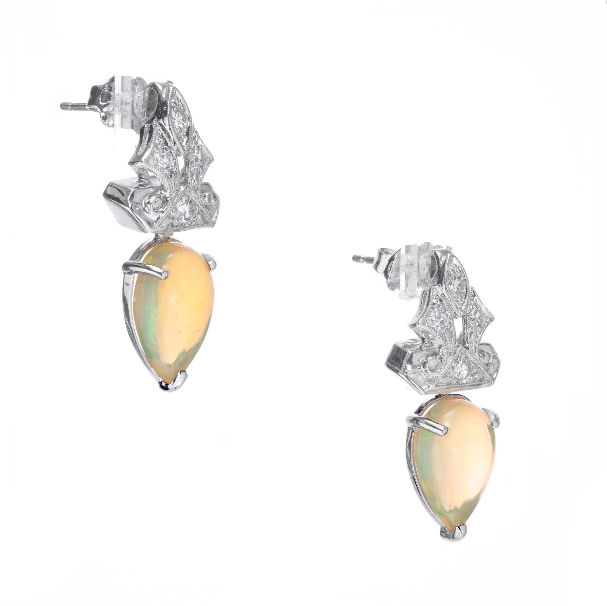 Opal and diamond dangle earrings. 2 translucent pear shaped Opals with 8 round accent diamonds. Crafted in the Peter Suchy Workshop. 

2 pearl cabochon blue green and orange flash Opals, approx. total weight 3.51cts
8 Diamonds, approx. total weight