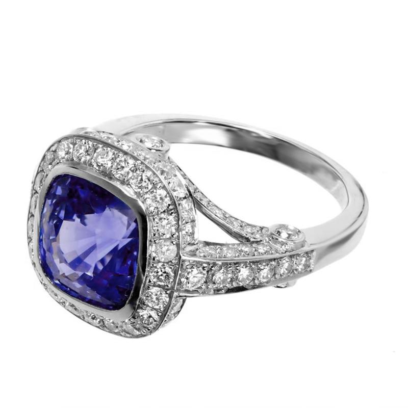 Stunning sapphire and diamond halo engagement ring. AGL certified cushion shape bezel set periwinkle 3.91ct center stone with a halo of full cut diamonds set in a platinum setting with diamonds along both shoulders, top and bottoms as well as the
