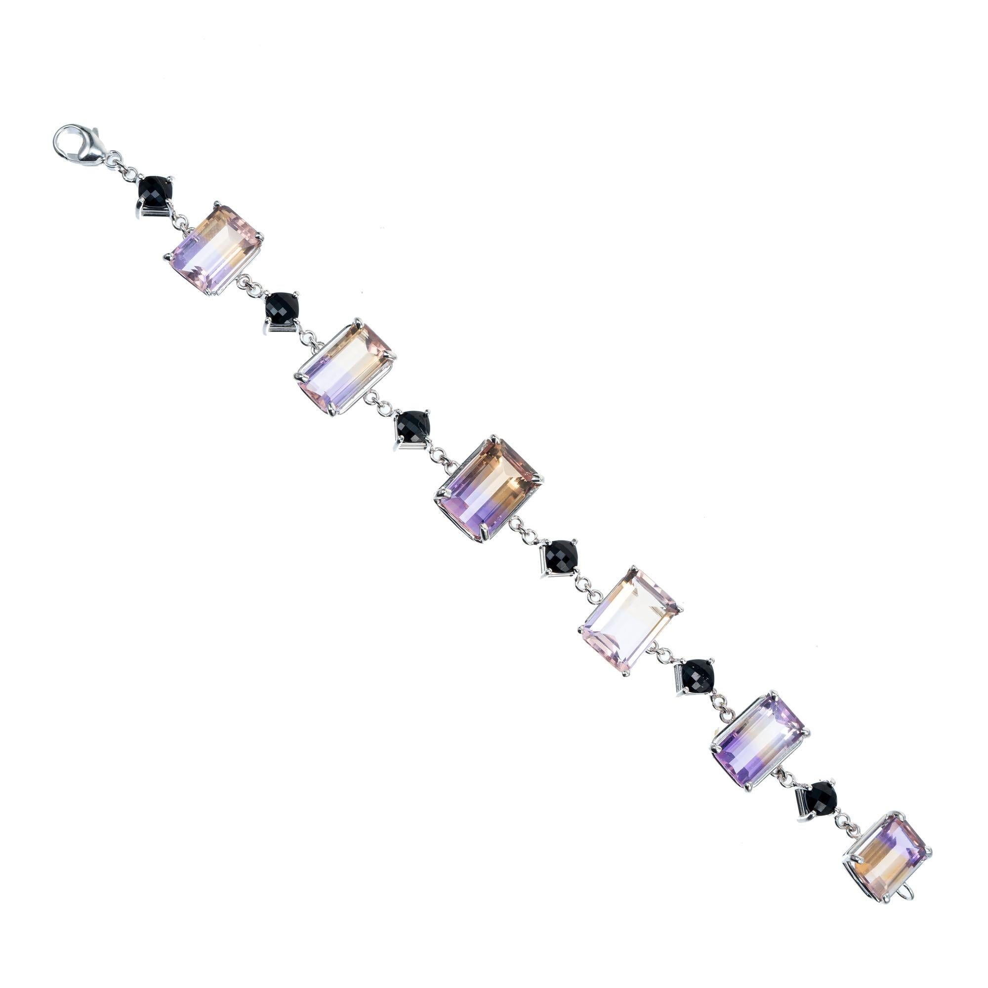 Ametrine and onyx bracelet. 6 emerald cut purple and yellow ametrines spaced by 6 quilt cut cabochon cushion cut black onyx in 14k white gold, 7 inches. From the Peter Suchy workshop

6 emerald cut purple to yellow ametrine, approx. 40.00cts
6 quilt