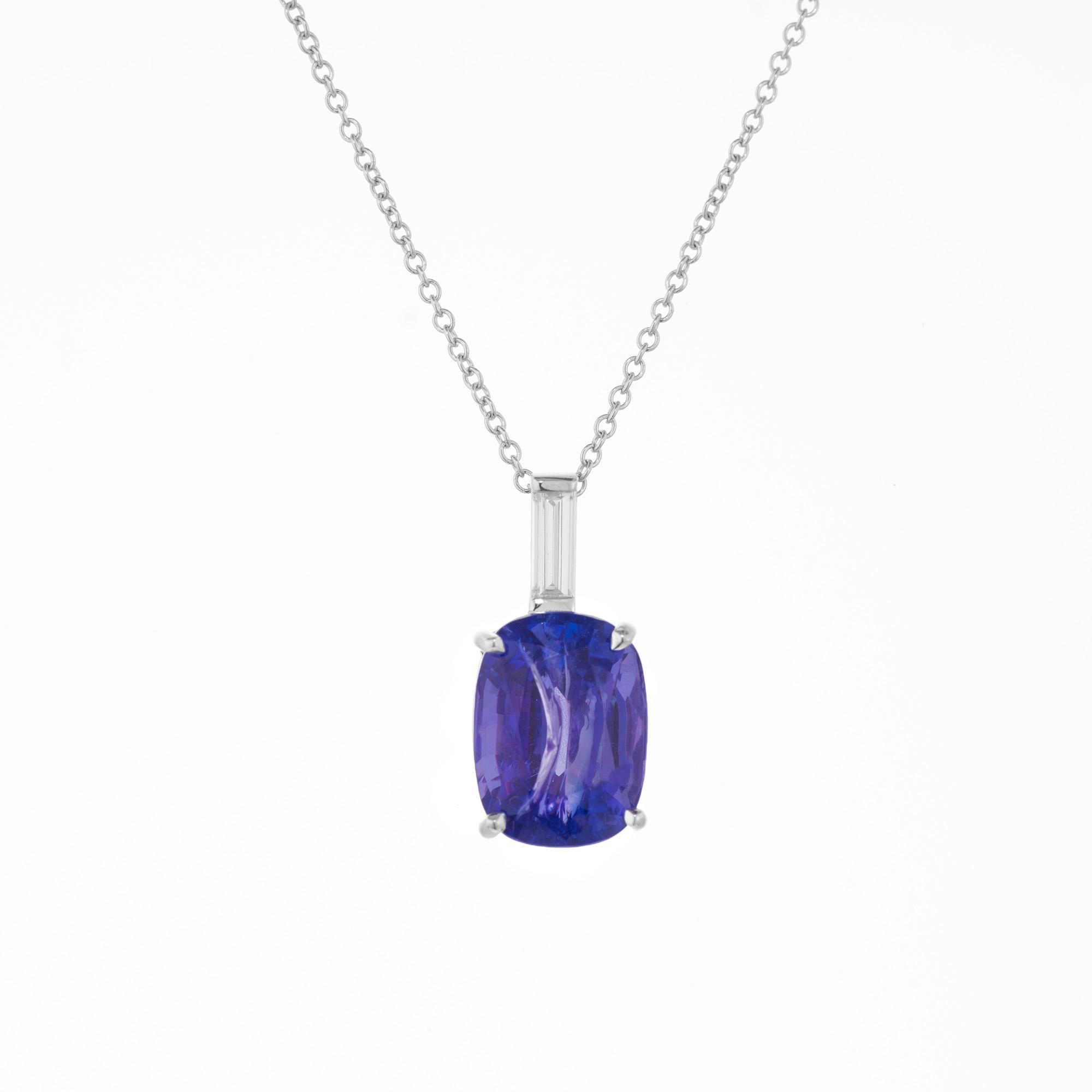 Bright purplish blue oval 4.47 carat tanzanite mounted in a 14k white gold four prong basket setting. Accented with on elongated straight cut baguette diamond. The chain measures at 16 inches. The violet-blue hue of the tanzanite paired with the