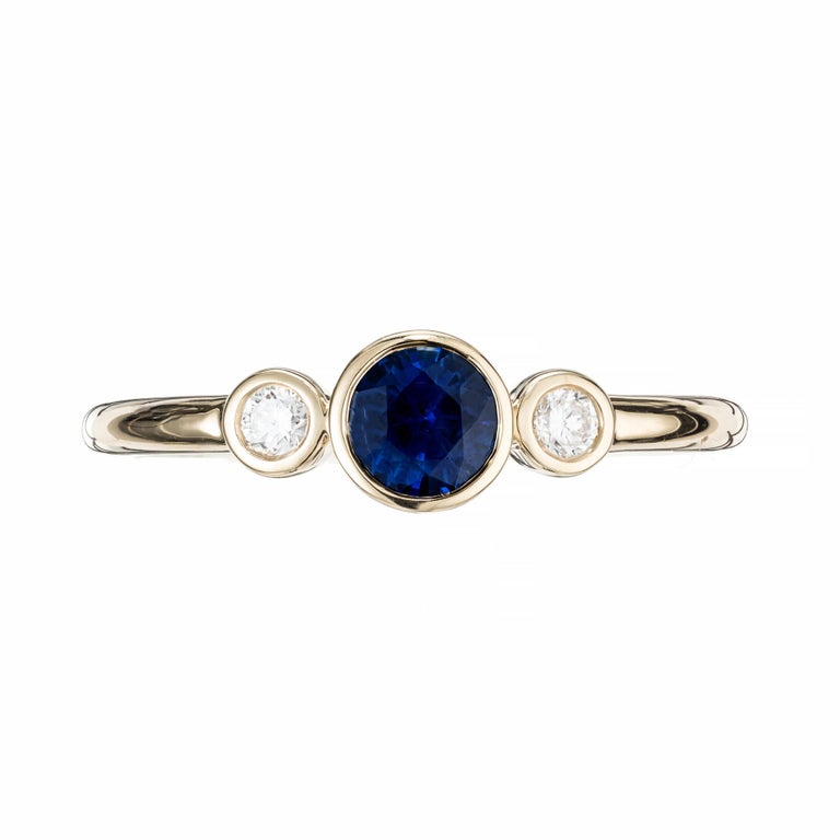 Blue sapphire and diamond engagement ring. Bezel set round sapphire with 2 bezel set diamonds in 18k yellow gold. Designed and crafted in the Peter Suchy workshop.

1 royal blue sapphire, approx. .49cts
2 round brilliant cut diamonds, G-H VS approx.