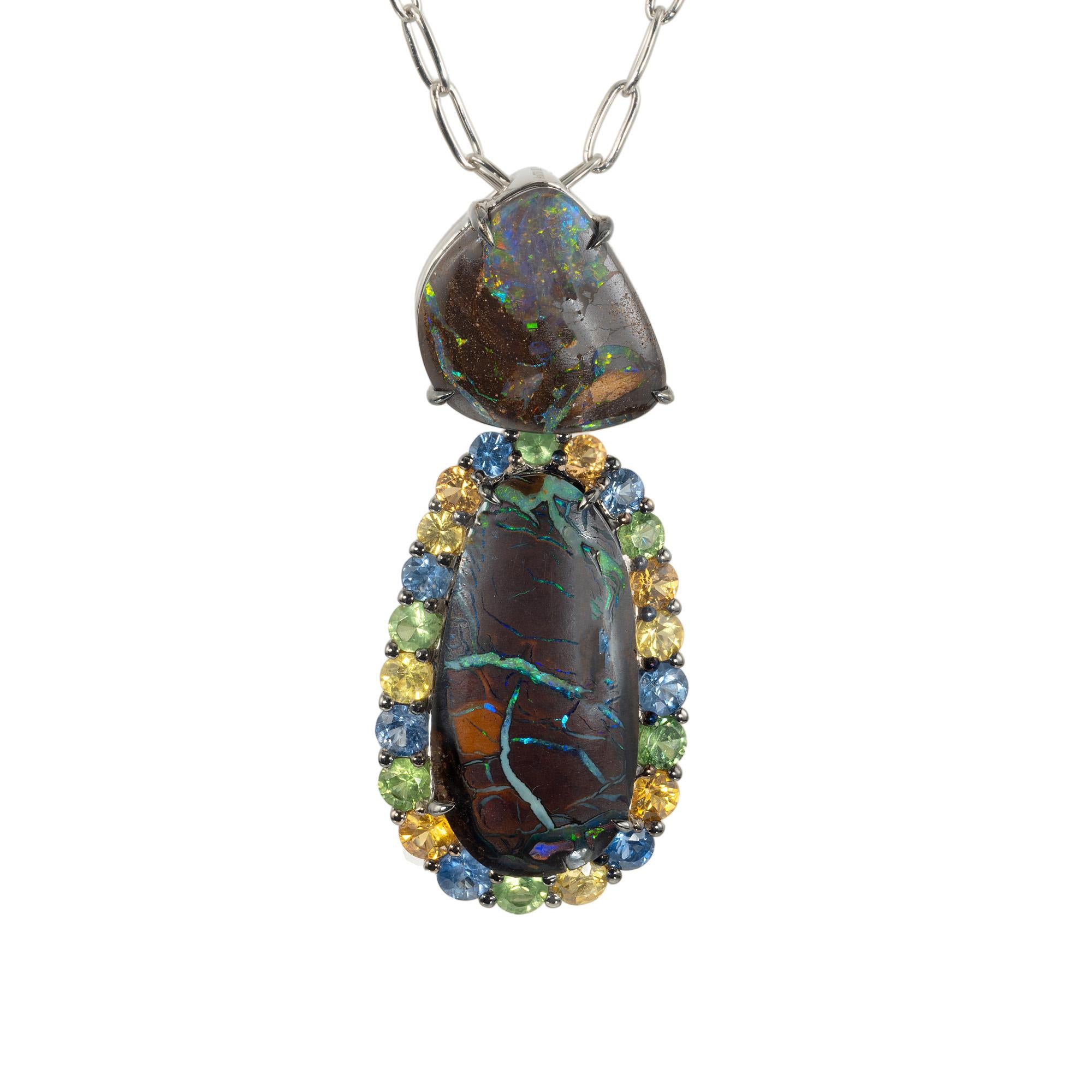 Collier pendentif unique en son genre composé d'opale, de saphir et de tsavorite. Deux opales de roche naturelles, l'une non taillée et l'autre de forme ovale, rehaussées d'un halo de saphirs et de grenats de couleur naturelle, pendent au bout d'un