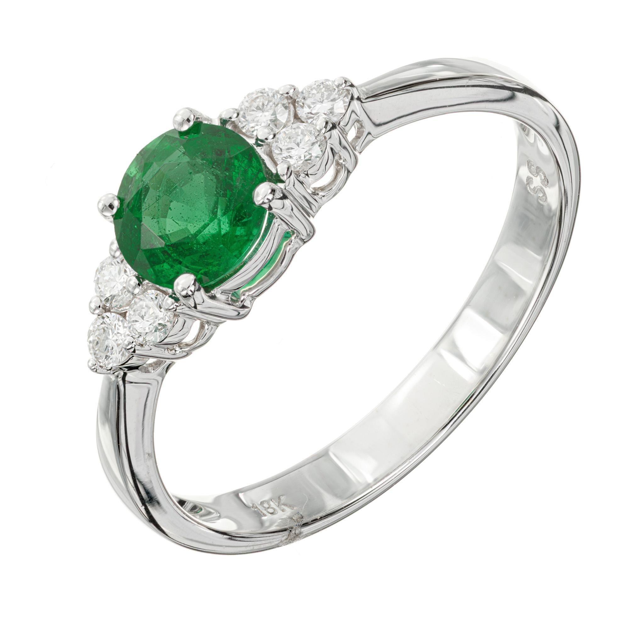 Emerald and diamond engagement ring. Bright green .57 carat round natural emerald center stone. 18k white gold setting with 3 round diamonds on each side. Designed and crafted in the Peter Suchy Workshop.

1 round green emerald, approx. .57cts
6