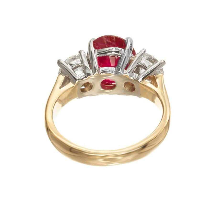 Experience timeless elegance with our Peter Suchy ruby and diamond three-stone engagement ring. At the center of this mounting is a 3.16ct oval Ruby that is flanked by tow round brilliant cut diamonds that have a total weight of 1.12cts. The setting