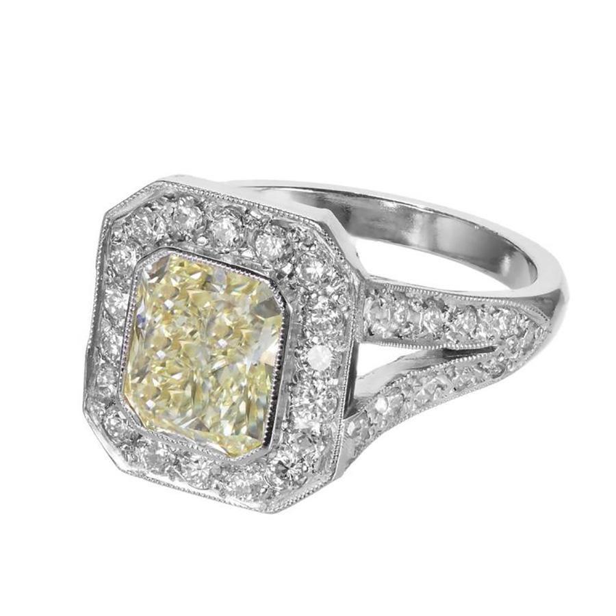 Handmade yellow diamond with diamond halo platinum engagement ring. The EGL certified 2.06ct center stone is a natural fancy yellow cushion cut diamond of rectangular shape with squared off corners. Top to bottom and side to side brilliance. Set in