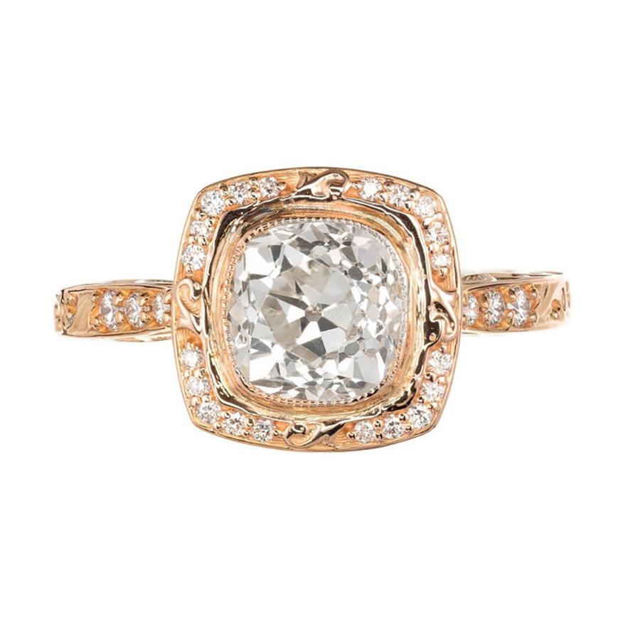 Peter Suchy square scroll cushion cut bezel set, simple halo design engagement ring. At the center is an old mine brilliant cut 1.54 diamond that is mounted in 18k rose gold with scroll shoulders and sides. The halo consists of round diamonds that