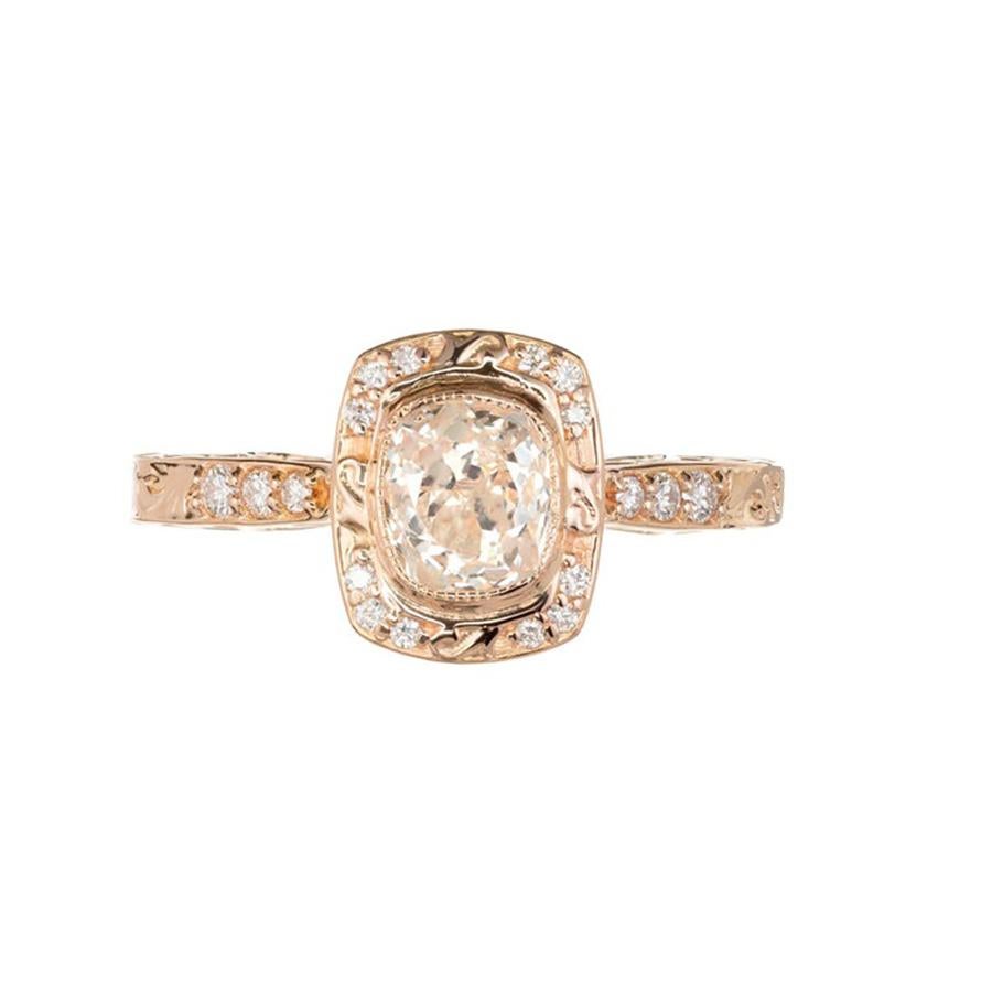 Anello di fidanzamento con diamante aureolato semplice incastonato a cuscino di Peter Suchy. Spalle e lati a voluta. Incastonatura in oro rosa 18 carati che permette di posizionare una fede nuziale a filo dell'anello. La pietra risale alla fine del