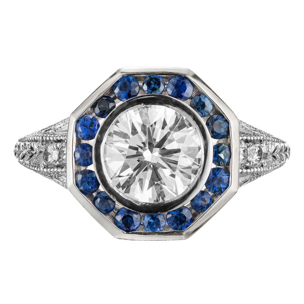 Diamond and sapphire engagement ring. GIA certified round center stone set in a pierced, hand engraved platinum 8 sided setting with a bright blue round Sapphire halo and round diamond accents. 

1 round diamond, approx. total weight 1.23cts, G,
