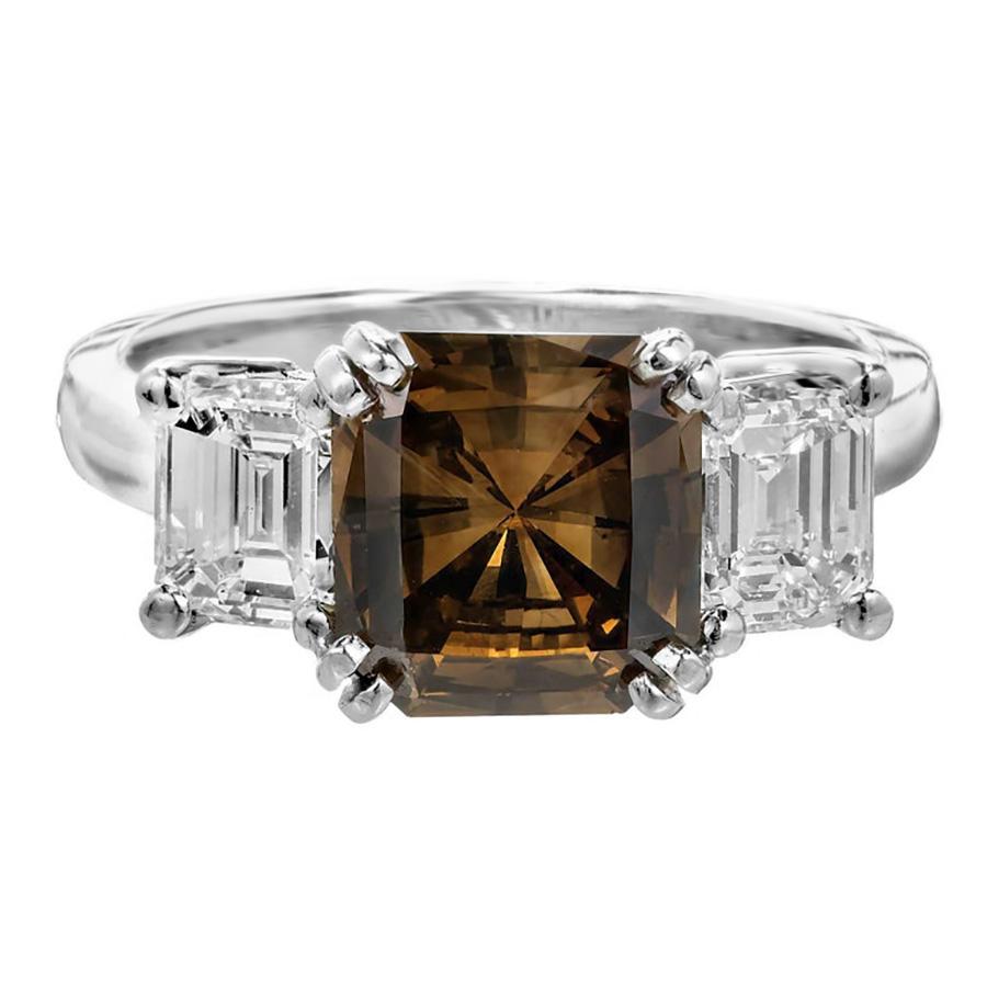 The Peter Suchy GIA certified 2.14ct. natural fancy dark orange brown radiant cut diamond three stone engagement ring. The square cut brown center diamonds is double prong set in platinum, glowing with a rich intensity reminiscent of the earth's