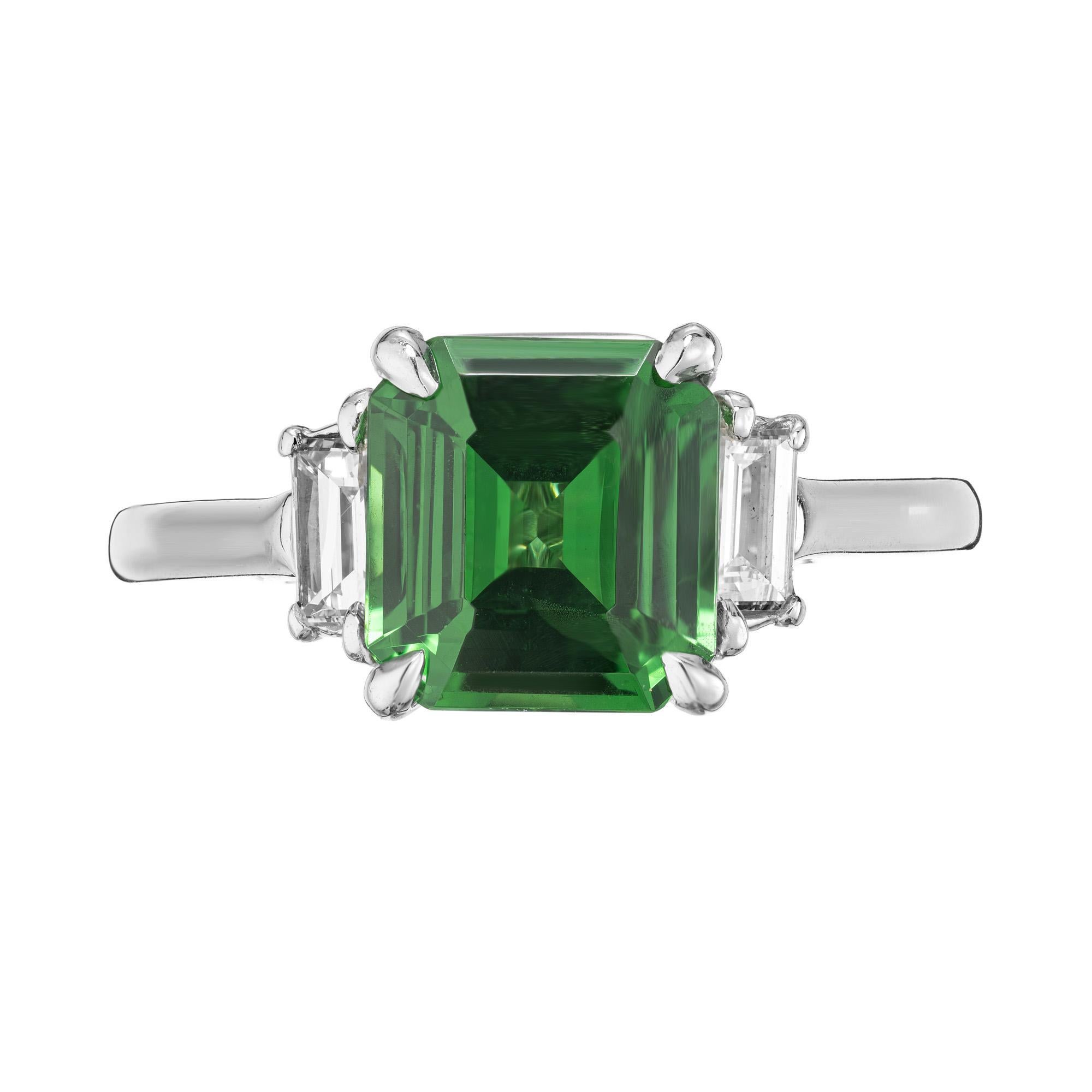 Rich green Tsavorite and diamond three stone ring. At the center of this ring is a 2.59ct octogonal shaped Tsavorite Garnet with a deep vibrant green hue green coloring. Mounted in a platinum setting and accented by one emerald cut diamond on each
