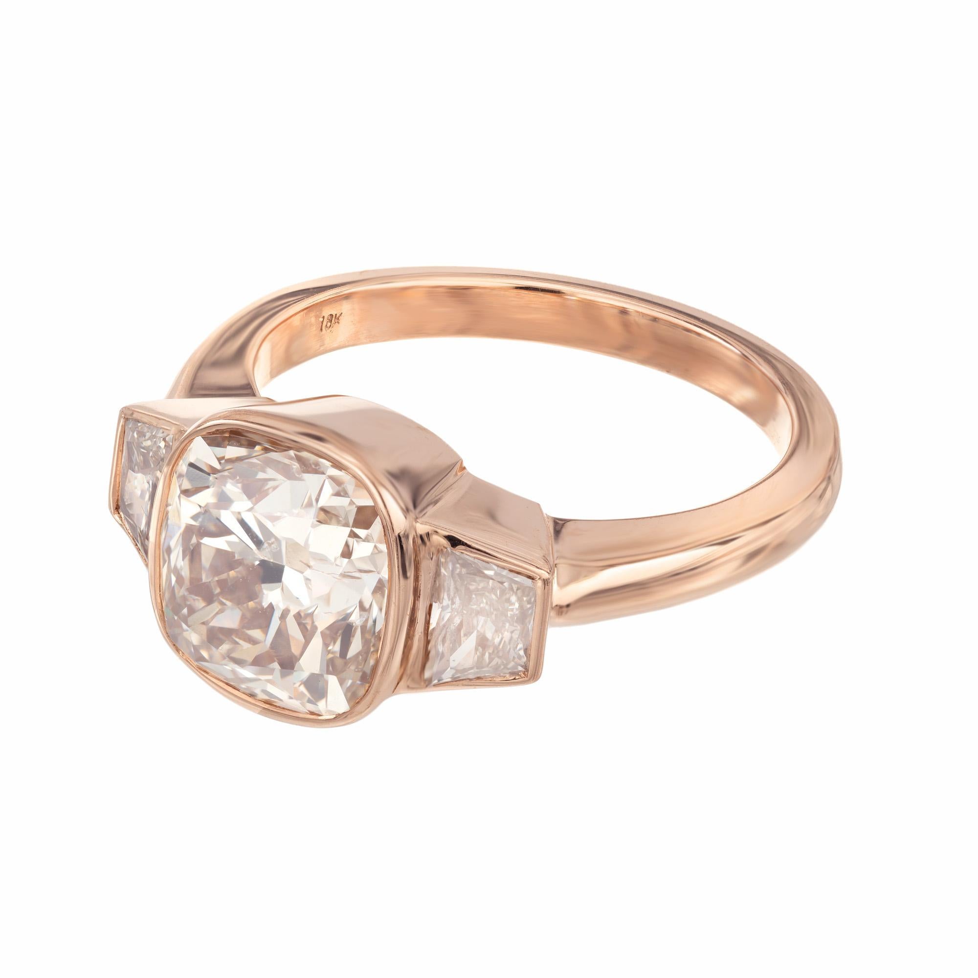 Spectacular Art Deco estate diamond three-stone engagement ring. At the center is a 1930's 3.01ct cushion cut diamond in a 18k rose gold bezel mounting. Accented by 2 vintage trapezoid, matching side diamonds with a total carat weight of .57cts. The