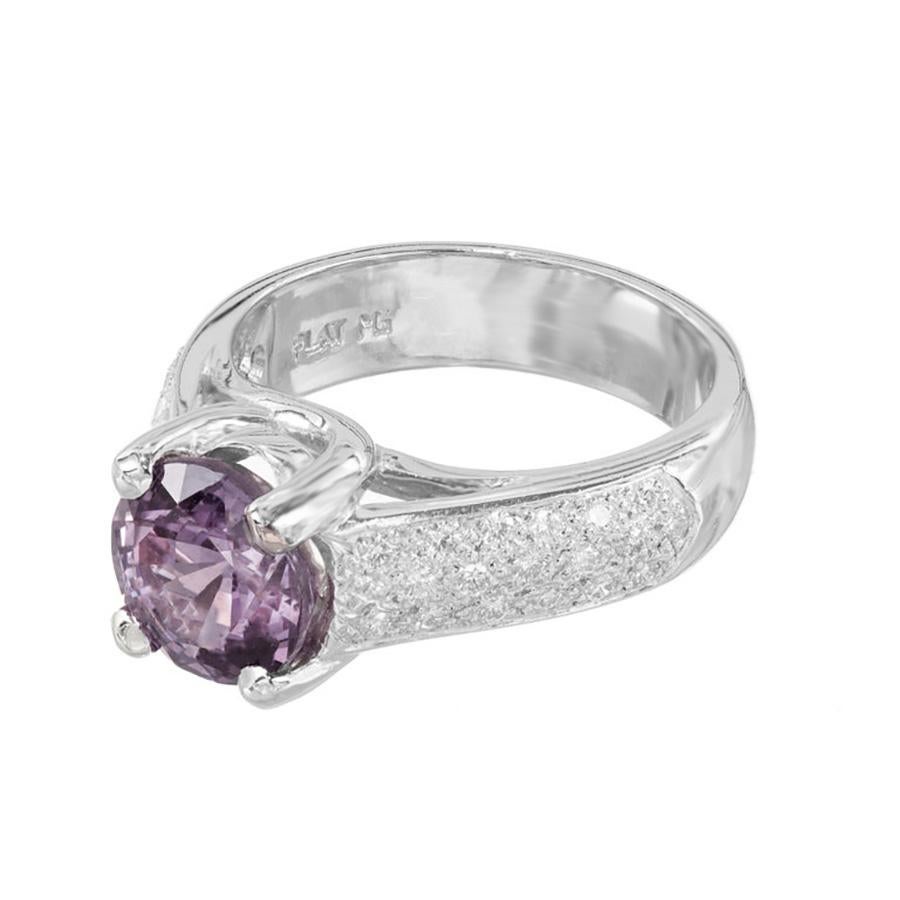 Designed and crafted by the Peter Suchy Workshop, this exquisite engagement ring features a mesmerizing 3.13ct purple round brilliant cut sapphire at its center, nestled in a luxurious platinum setting. The alluring hue of the purple sapphire is