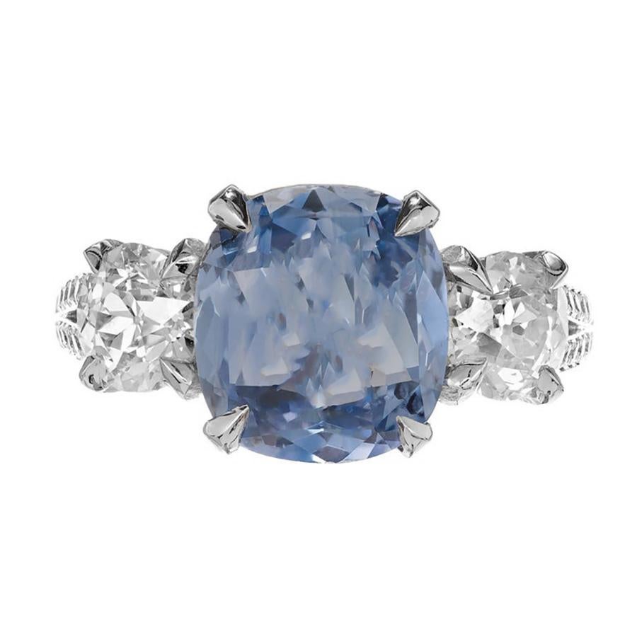 Anillo de compromiso Peter Suchy de tres piedras, zafiro y diamantes. El zafiro central azul claro brillante es talla cojín antiguo con un matiz bígaro. Moderadamente incluida. Los diamantes son brillantes y de talla antigua. Certificado GIA. 

1