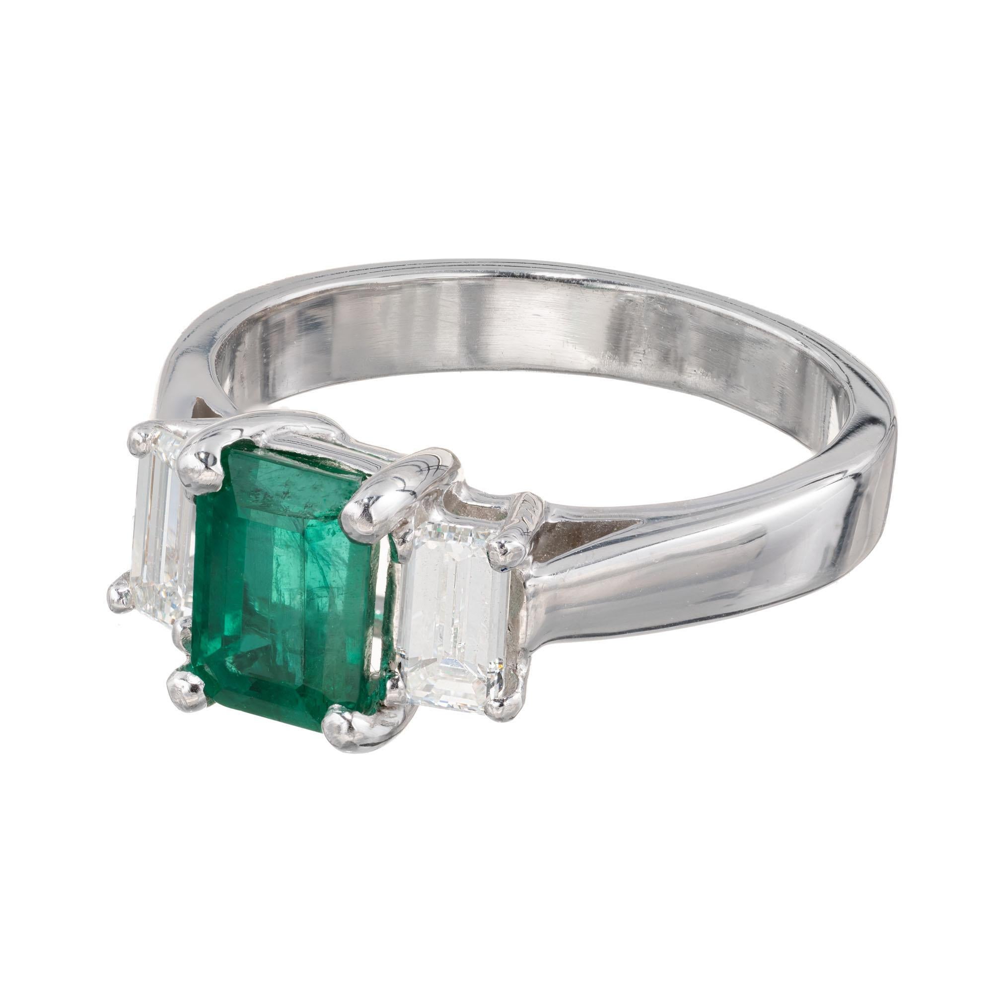 Peter Suchy three-stone emerald and diamond engagement ring. Emerald center stone with two emerald cut side diamonds in a platinum setting created by the Peter Suchy Work Shop. GIA certified.  

1 octagon cut green emerald MI, approx. 1.11cts GIA