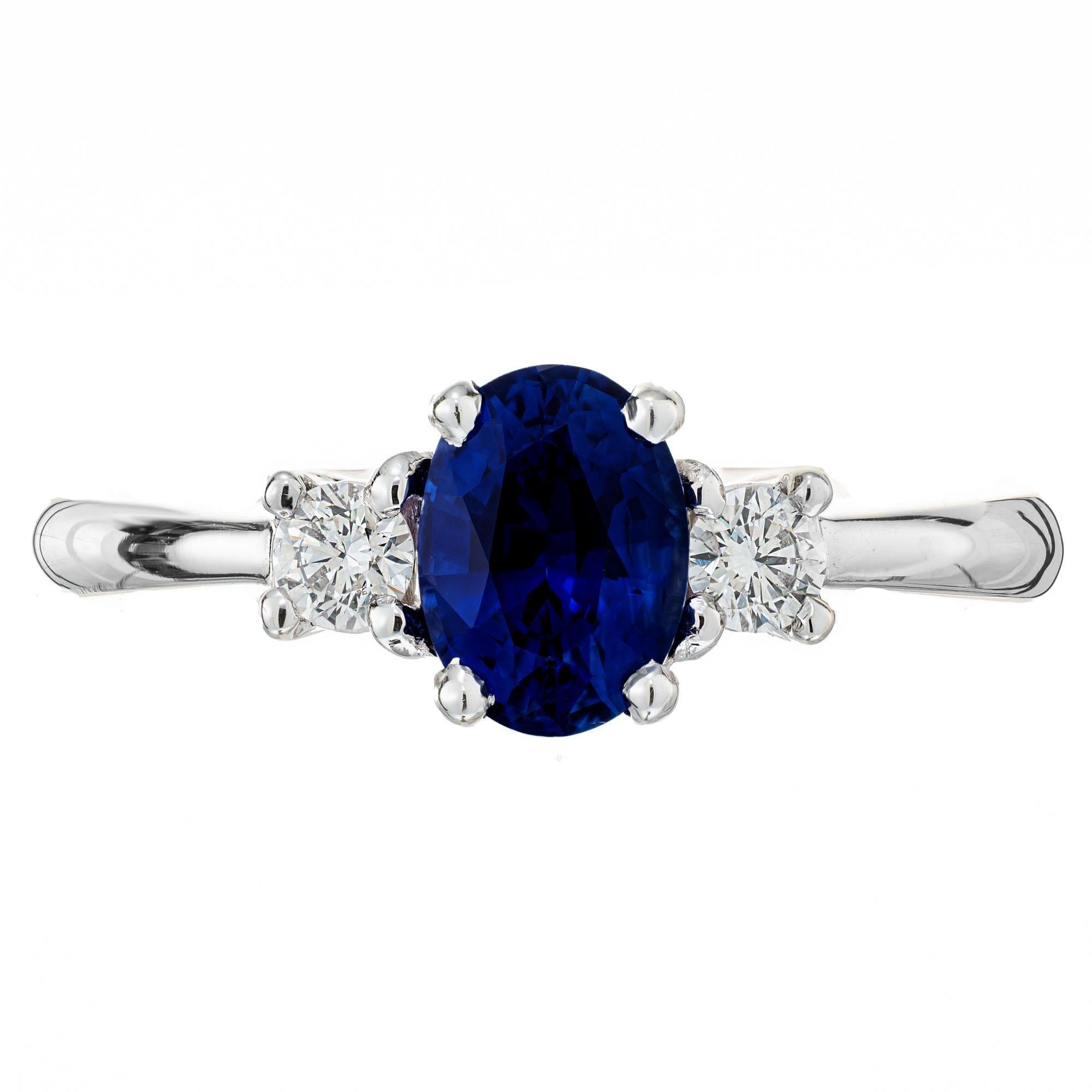 Sapphire and diamond three-stone engagement ring. GIA certified oval center 1.11ct center stone in a 14k white gold setting with 2 round brilliant cut side diamonds. Crafted in the Peter Suchy Workshop. 

1 oval bright blue sapphire, approx. 1.11cts