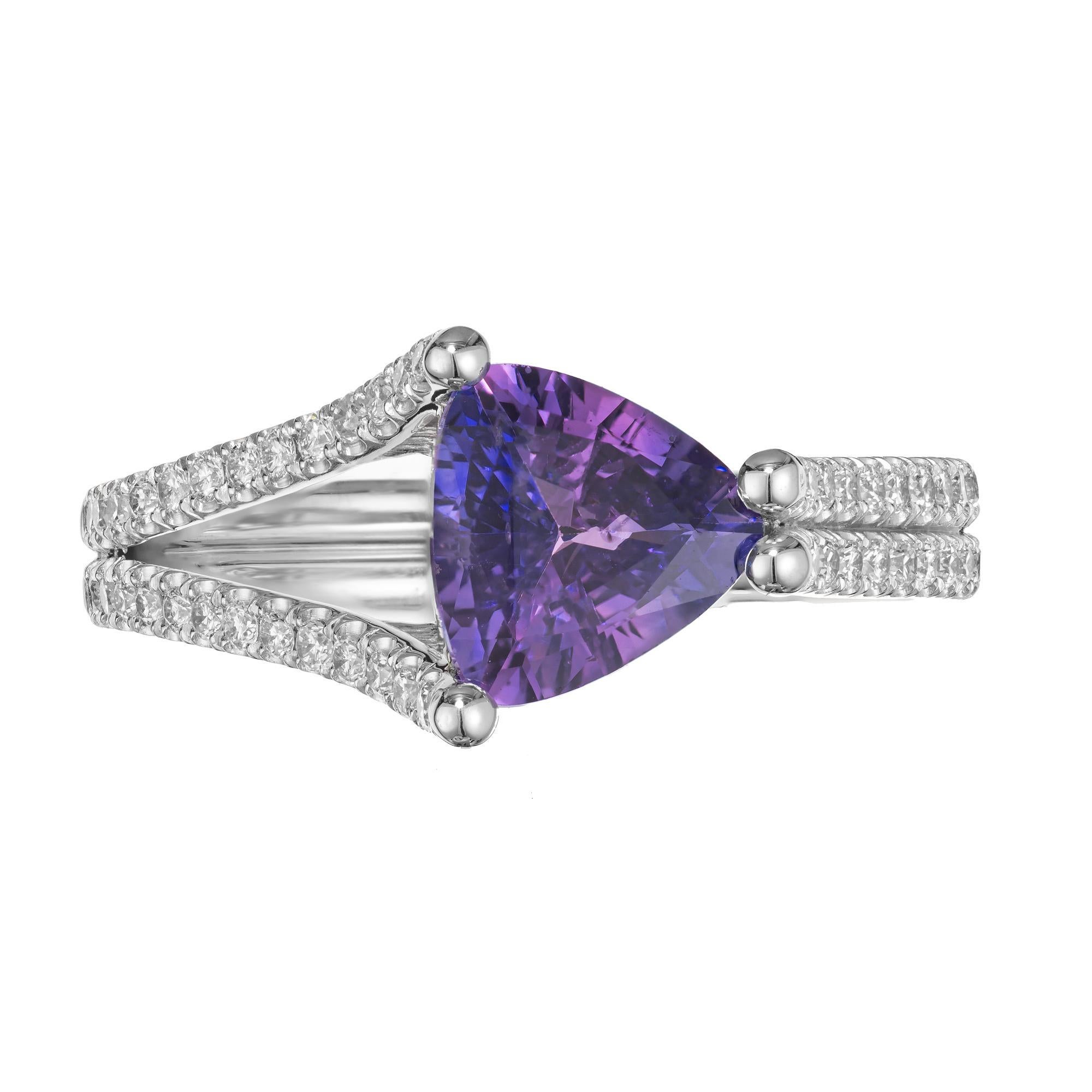 Violet sapphire and diamond engagement ring. Spectacular bright violet triangular cut sapphire mounted in an 18k white gold setting. One side of the setting is as split shank that becomes a double shank on the other side. with 54 round brilliant cut