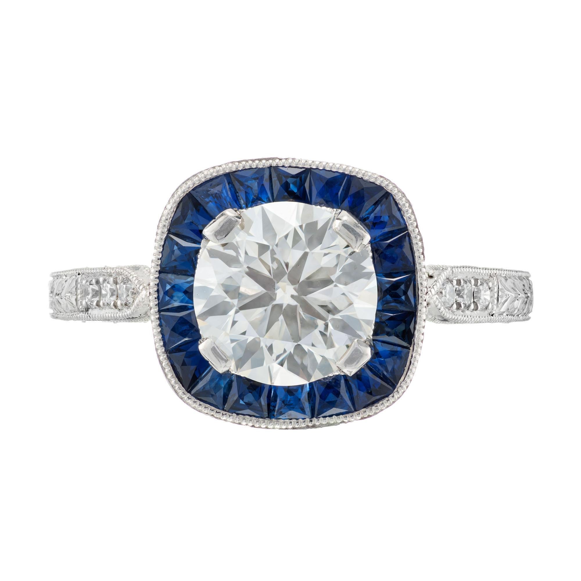 Peter Suchy diamond and sapphire platinum engagement. GIA certified round center stone with a halo of calibre sapphires in a platinum hand engraved setting. 

1 round diamond L VVS2, approx. 1.50ct GIA Certificate # 5172969093
20 calibre cut blue
