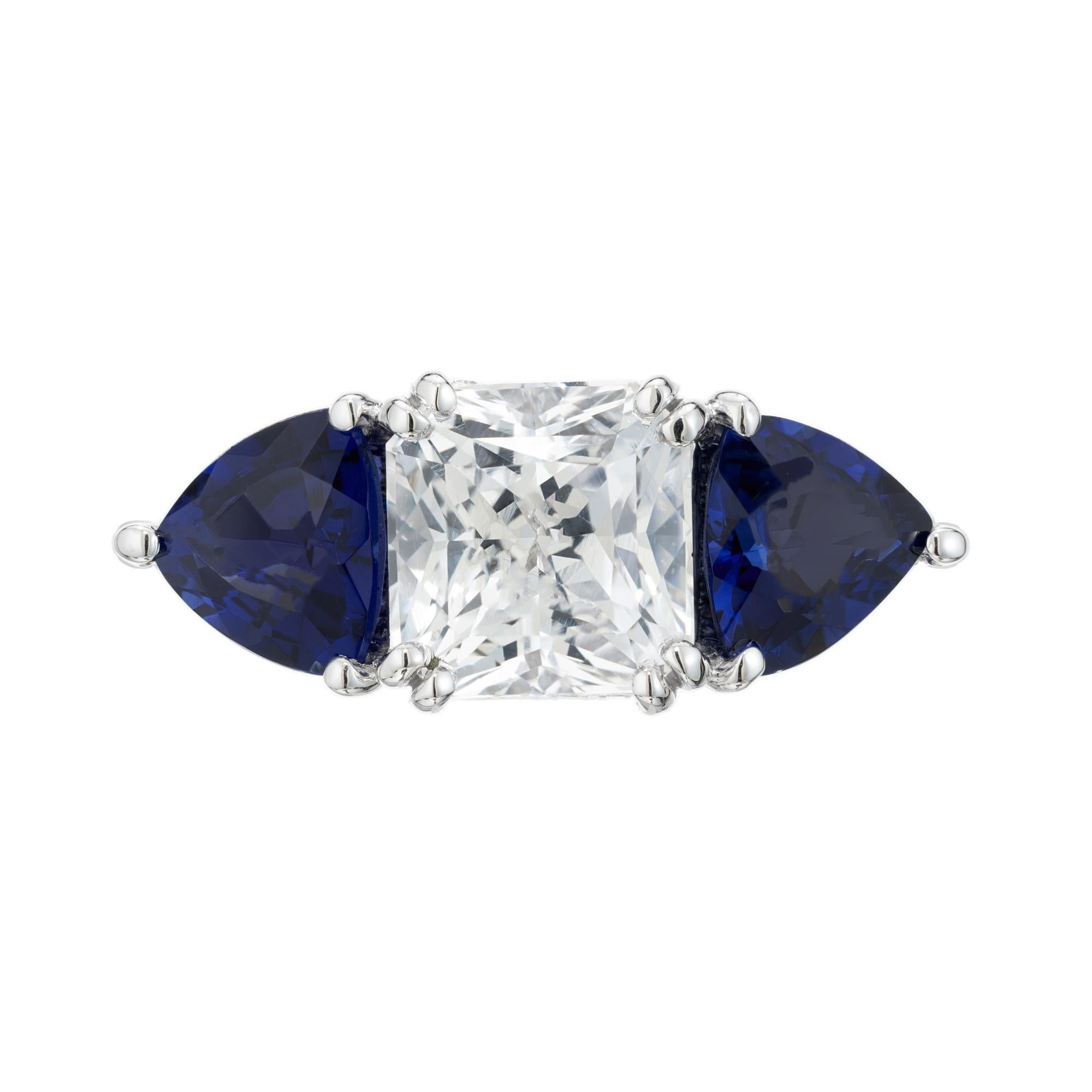One of a kind sapphire and diamond engagement ring. This ring features a GIA certified 2.22ct octagonal white sapphire center stone, mounted in a platinum three-stone setting accented with a triangular cut blue sapphire on each side. The ring is