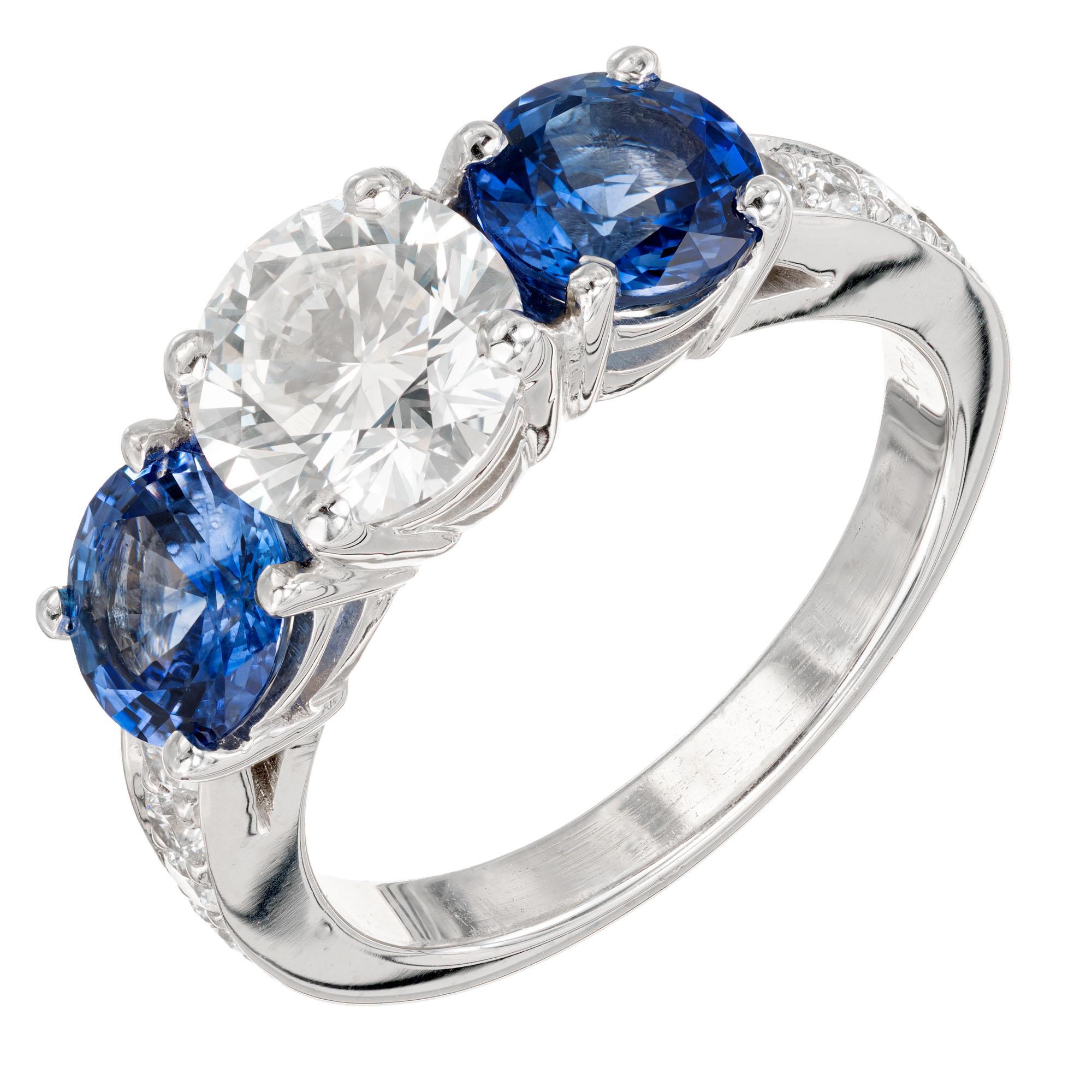 Peter Suchy diamond and sapphire three-stone engagement ring. Ideal cut 1.45 carat GIA certified diamond center stone with two round brilliant cut blue sapphires in a three-stone setting with round accent diamonds along both sides of the shank. The