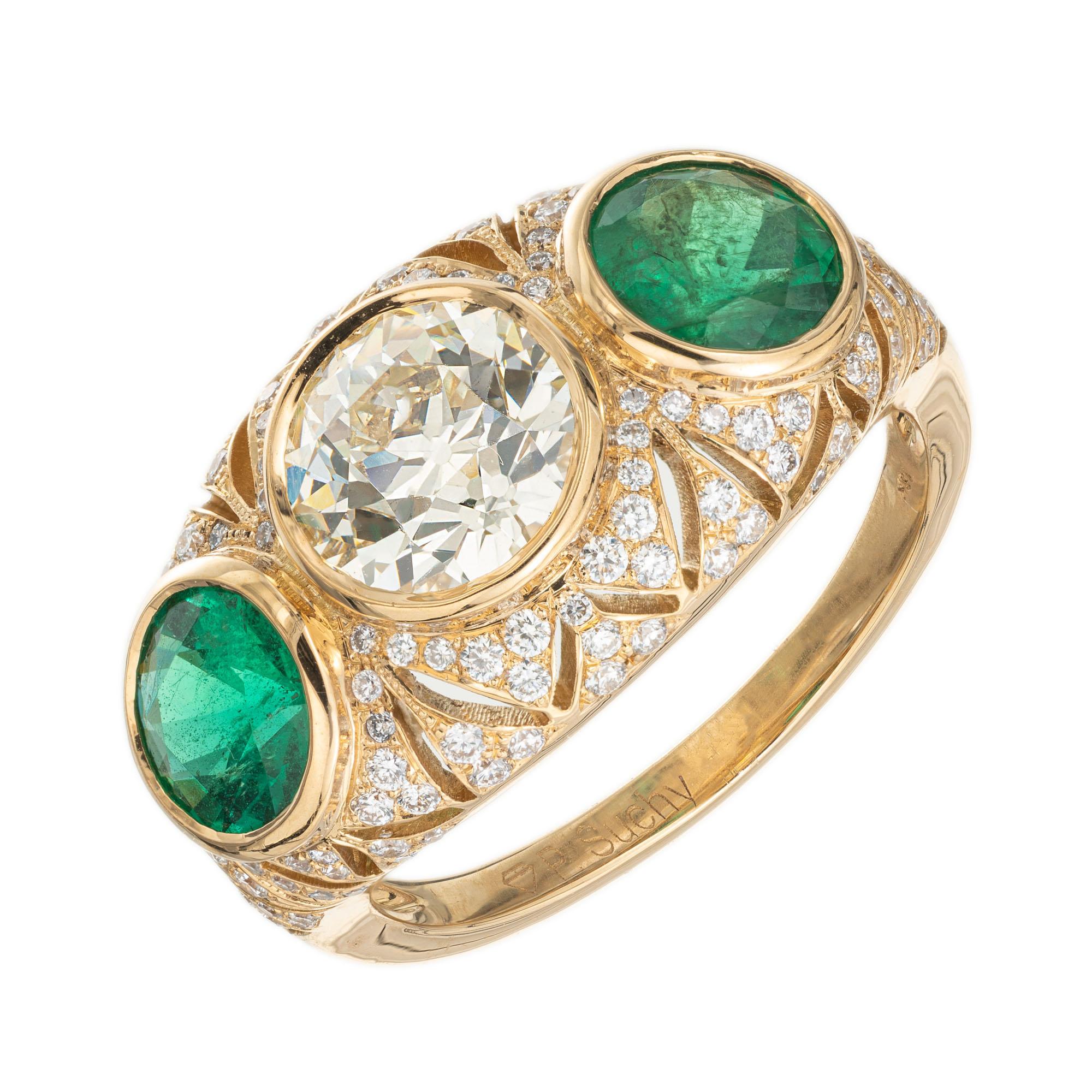 Peter Suchy antique inspired handmade diamond and emerald ring. GIA certified Old European cut center diamond with 2 round emerald side stones in a 18k yellow gold three-stone setting with 130 round brilliant cut diamonds.  Some history- this was a