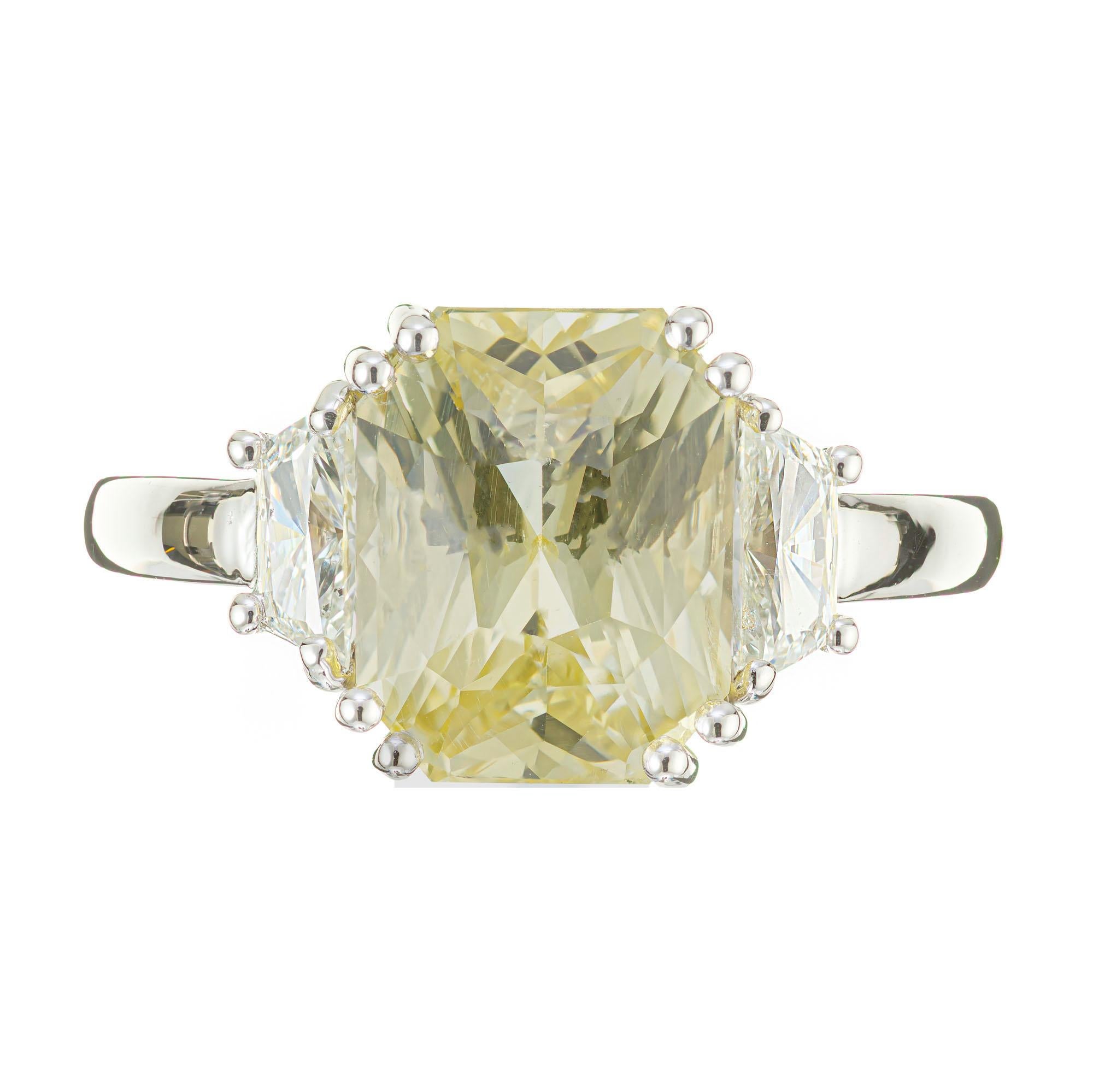 Yellow sapphire and diamond three-strong engagement ring. GIA Certified natural untreated octagonal sapphire circa 1915 from an Art Deco era estate. Set in a custom classic platinum three stone setting with 2 well matched trapezoid side diamonds.