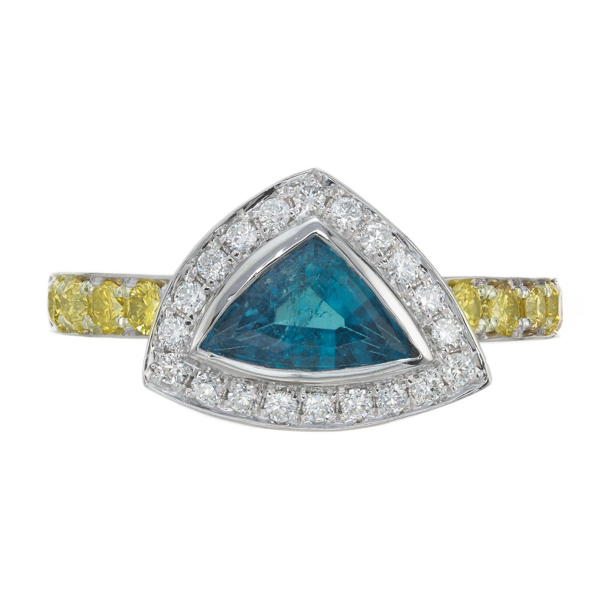 Tourmaline and diamond engagement ring. GIA certified Brazilian Paraiba deep blue triangular tourmaline center stone with a halo of 20 round white brilliant cut diamonds and 10 round brilliant cut fancy intense, natural yellow diamonds along the