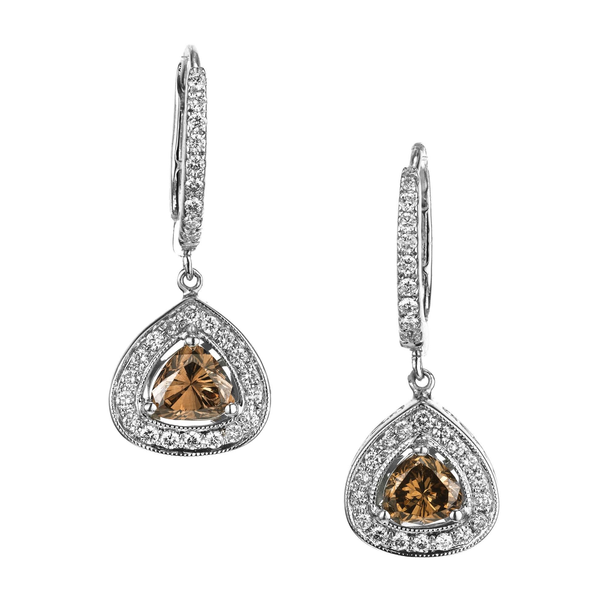 Adorn your ears with the exquisite beauty of these Peter Suchy GIA certified dangle earrings featuring .92 carat orange and brown heart shaped diamonds, each accented by a halo of round brilliant cut diamonds. Certified by the GIA as natural, fancy