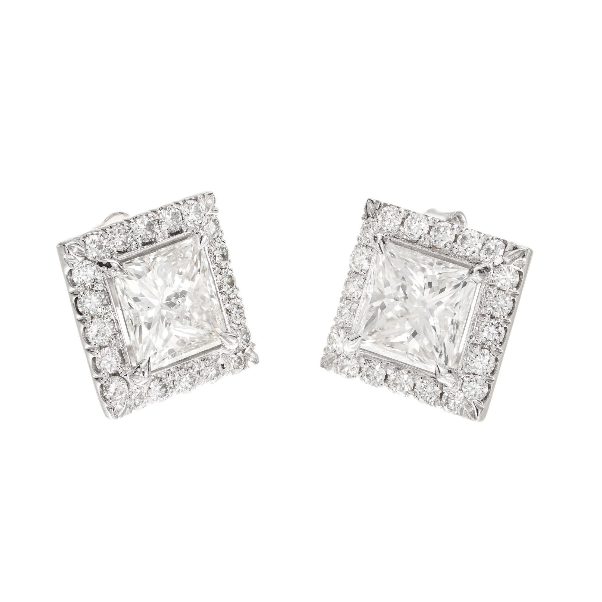 Peter Suchy set princess cut diamond halo earrings. Two square cut diamonds with 40 round brilliant cut diamond halo frames in 18k white gold.

1 square modified brilliant cut diamond, H I approx. 1.20cts GIA certificate # 1126611297
1 square