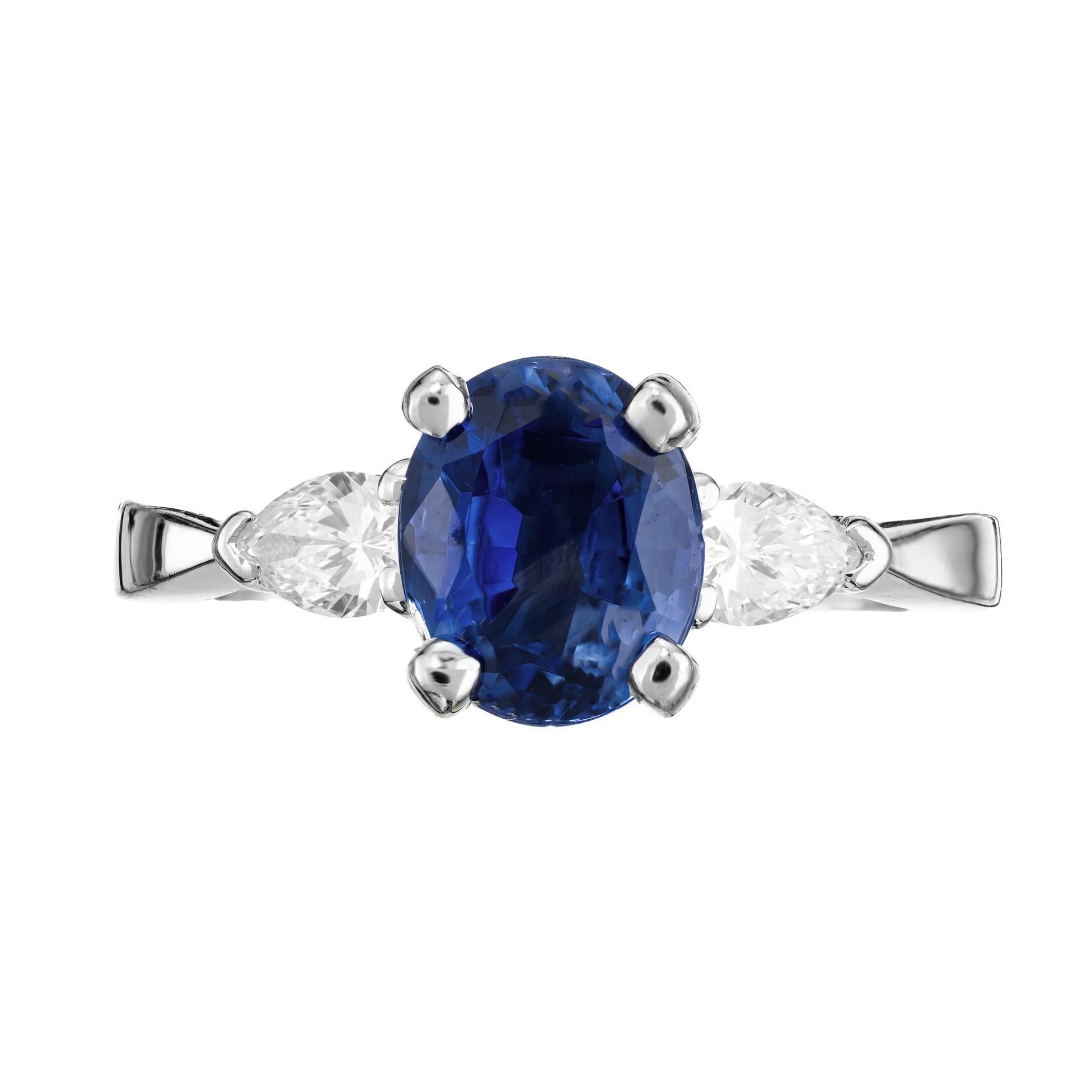 Peter Suchy rich bright blue sapphire and diamond three-stone engagement ring. The centerpiece is a captivating 2.02ct oval sapphire mounted in a platinum setting with a dazzling pear shaped diamond on each side of the gemstone, enhancing its