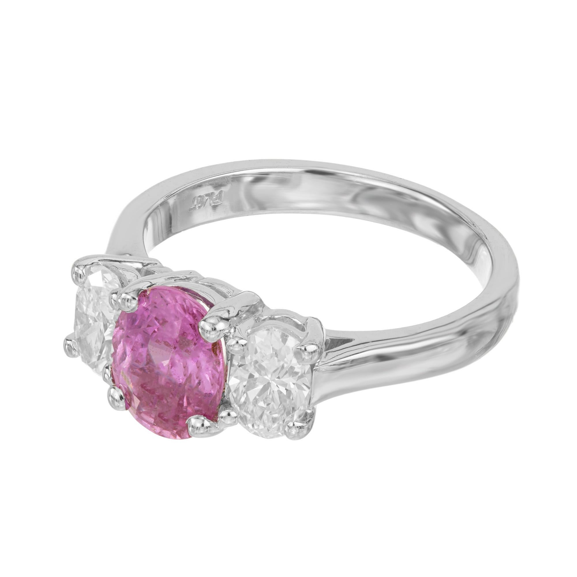 Peter Suchy oval purplish pink Sapphire and oval diamond three stone engagement ring. This exquisite ring features a stunning 1.82ct center sapphire mounted in a platinum setting, flanked by two dazzling diamonds totaling .90cts, on either side.