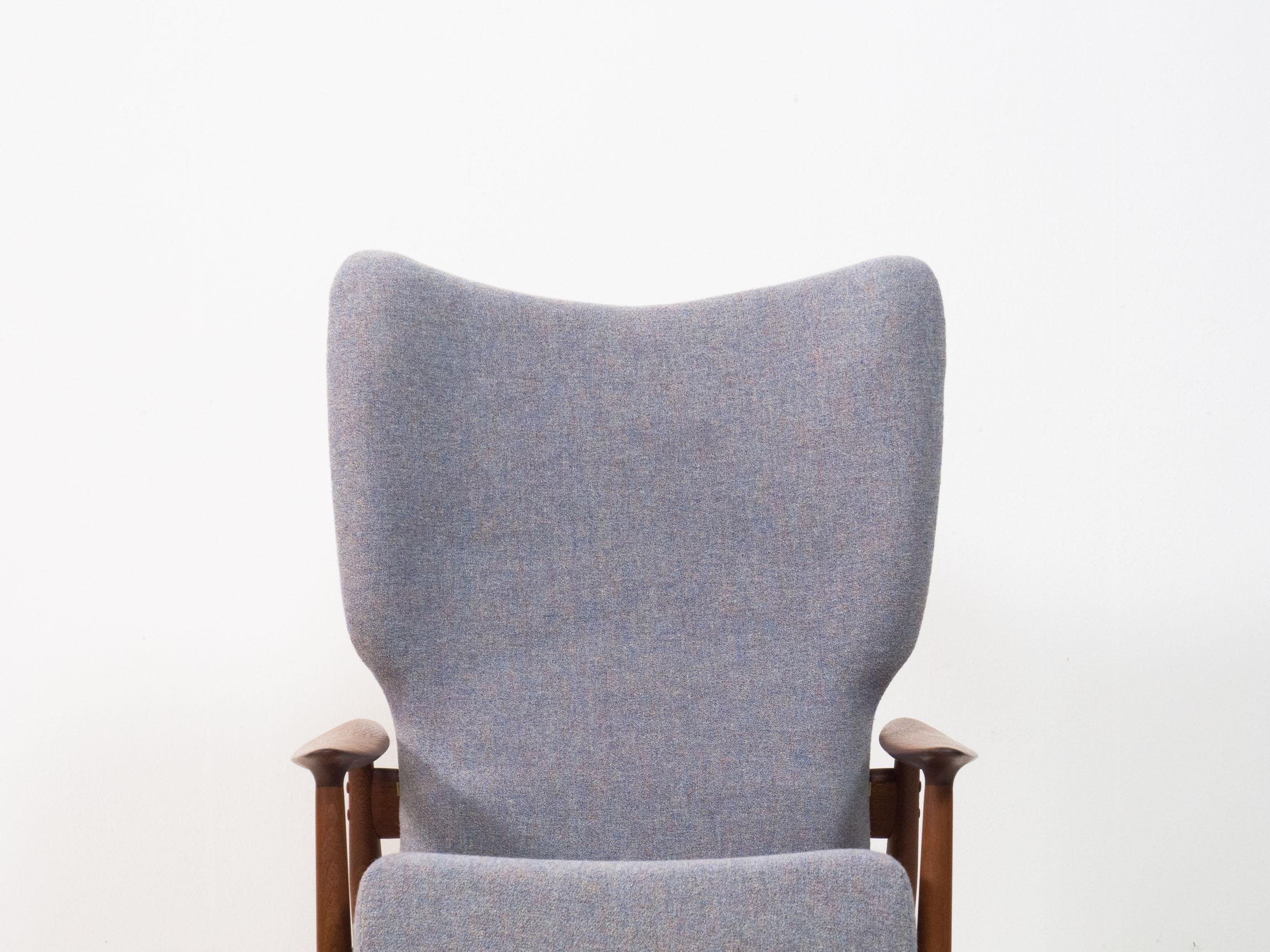 Wing back lounge chair designed by K. Rasmussen for Peter Wessel of Norway, 1960s.

This lounge chair has a solid teak frame and is newly upholstered in a blue/gray wool fabric. It reclines using two brass swivel mechanisms attached to the back. The