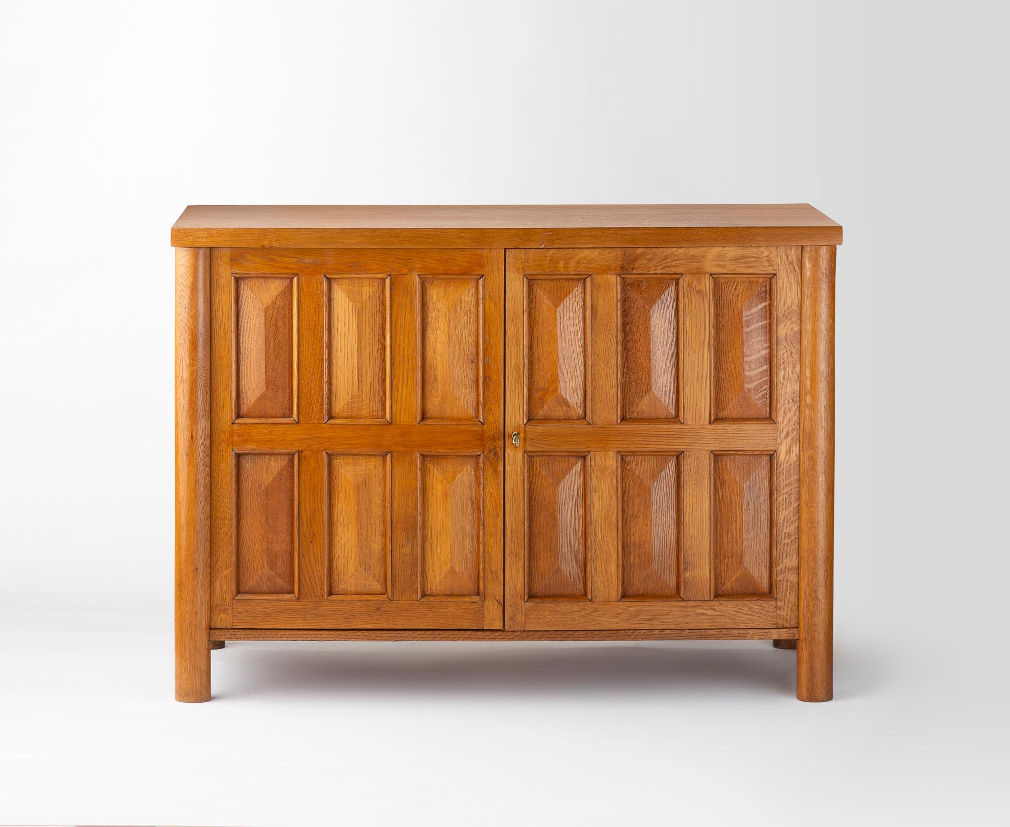 Questo mobile in rovere incarna la sobria eleganza e la funzionalità del design francese del periodo tra le due guerre. Di forma rettangolare e definita da linee pulite, poggia su quattro gambe cilindriche leggermente sfalsate. La facciata è