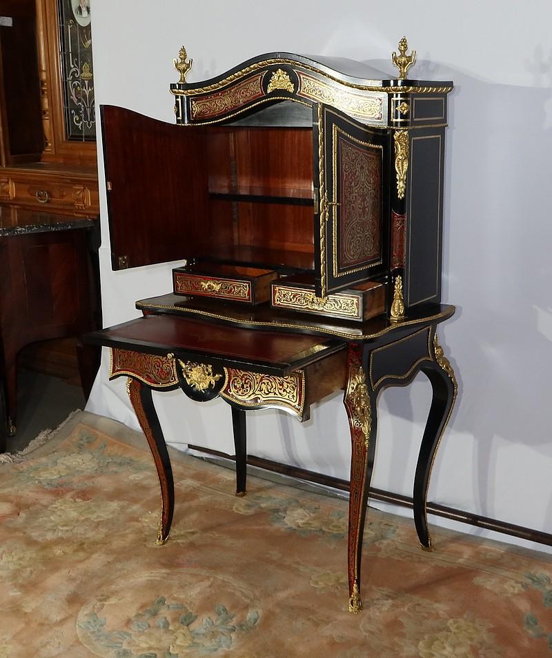 A ladies' piece of furniture in Boulle marquetry, richly ornamented with bronze and brass inlays.
This ebonized pearwood piece features a lower section with a table opening into a large drawer, topped with a writing tablet. A gilt and chiseled
