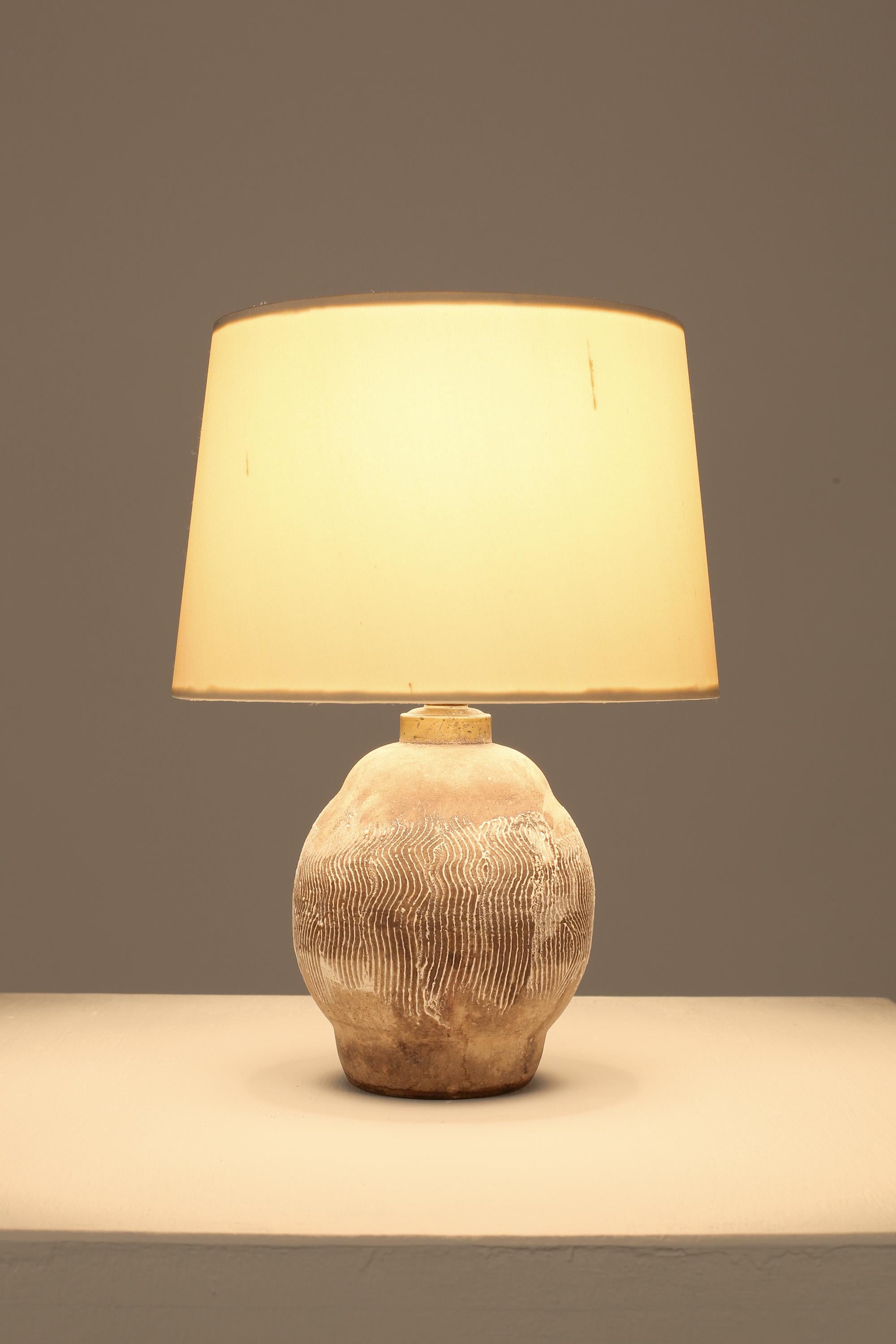 A charming petit Africanist style ceramic table lamp with plaster-like glaze and abstract etched designs, in the manner of Jean Besnard. French, c. 1930s. Supplied with a bespoke off-white dupion silk shade.