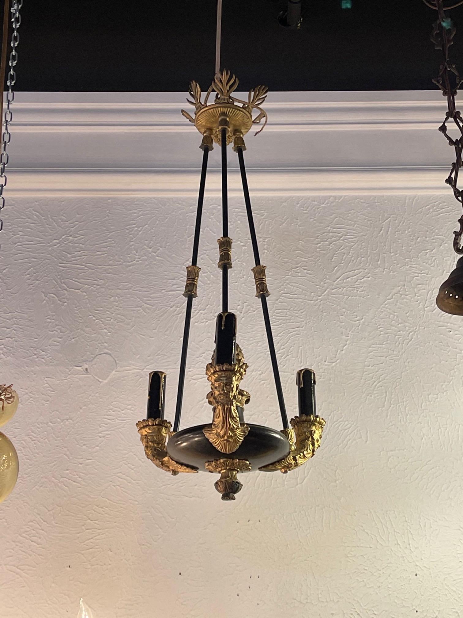 Rare small 19th century French Empire style gilt bronze chandelier with 3 lights. Interesting details including a male face on the arms. This gorgeous fixture makes a real impact!!