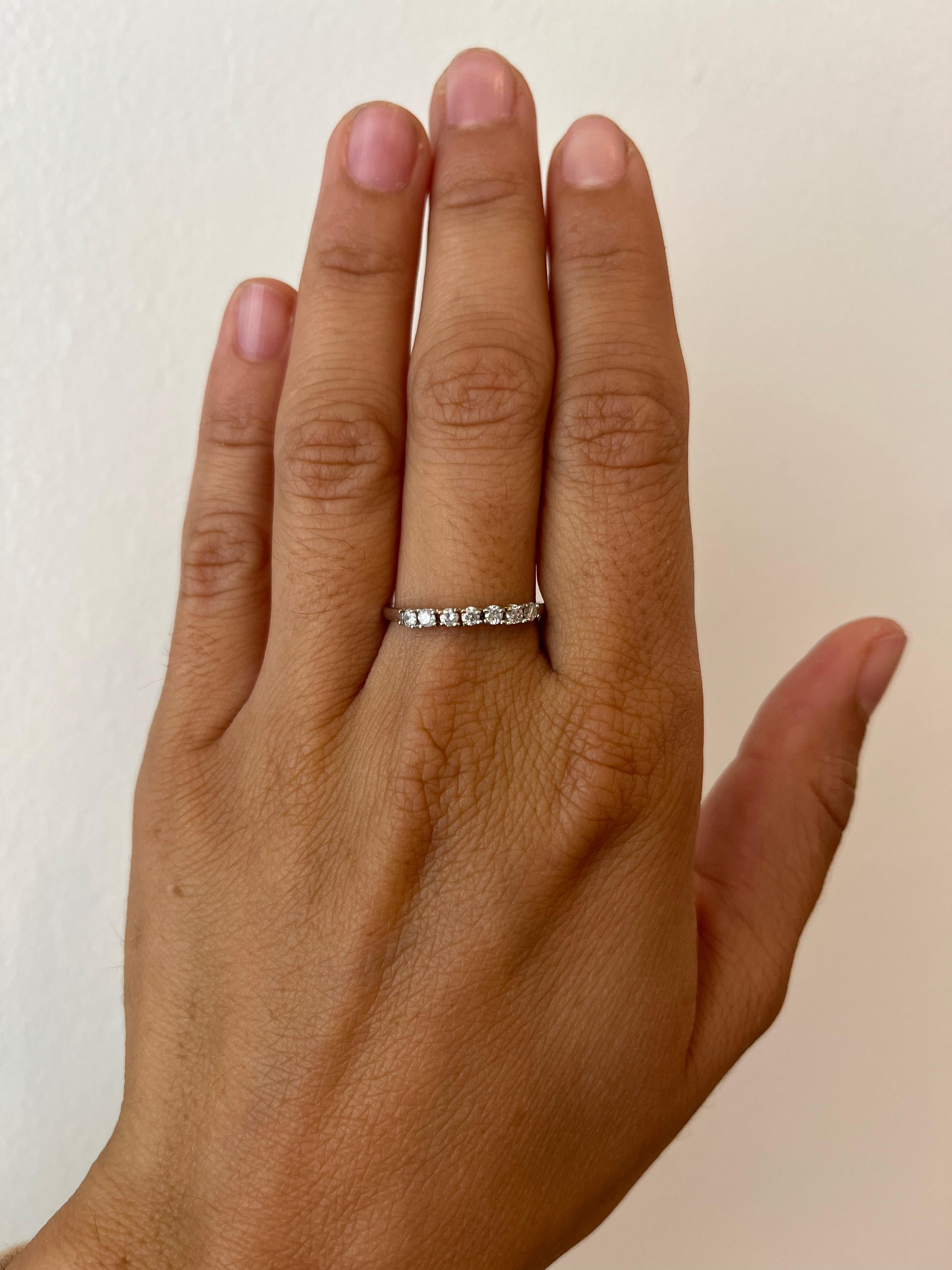 Esta pequeña y delicada alianza de 7 diamantes ofrece una hermosa línea de brillo. Los 7 diamantes redondos naturales suman 0,18 ct y están engastados en oro blanco de 14 quilates. Es una buena elección de anillo económico o de iniciación. De la