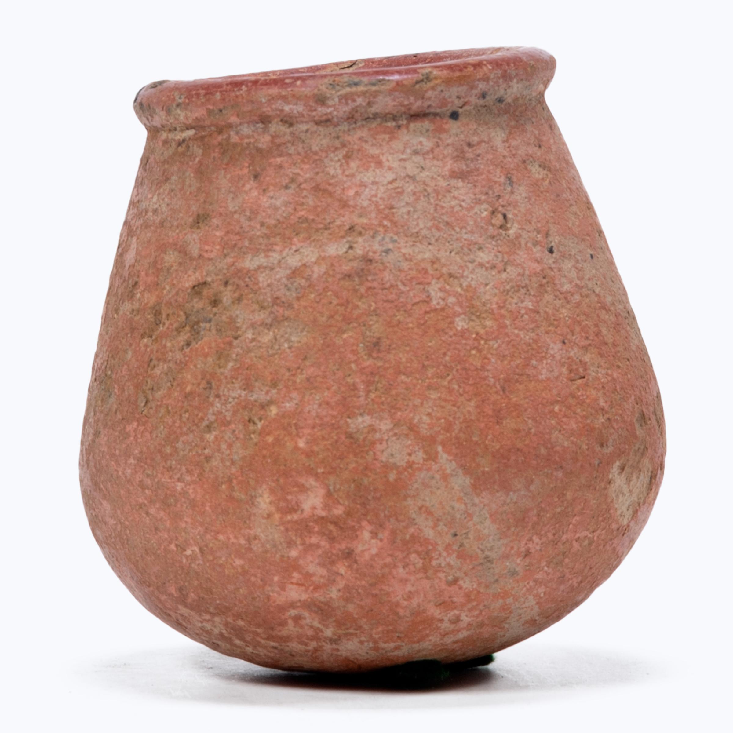 This petite hand-formed vessel bears a richly textured surface of worn red clay slip and dark smoke marks. Likely intended for everyday use, the simple bottle-form vessel reflects the skill of West African artisans, beautifully sculpted with