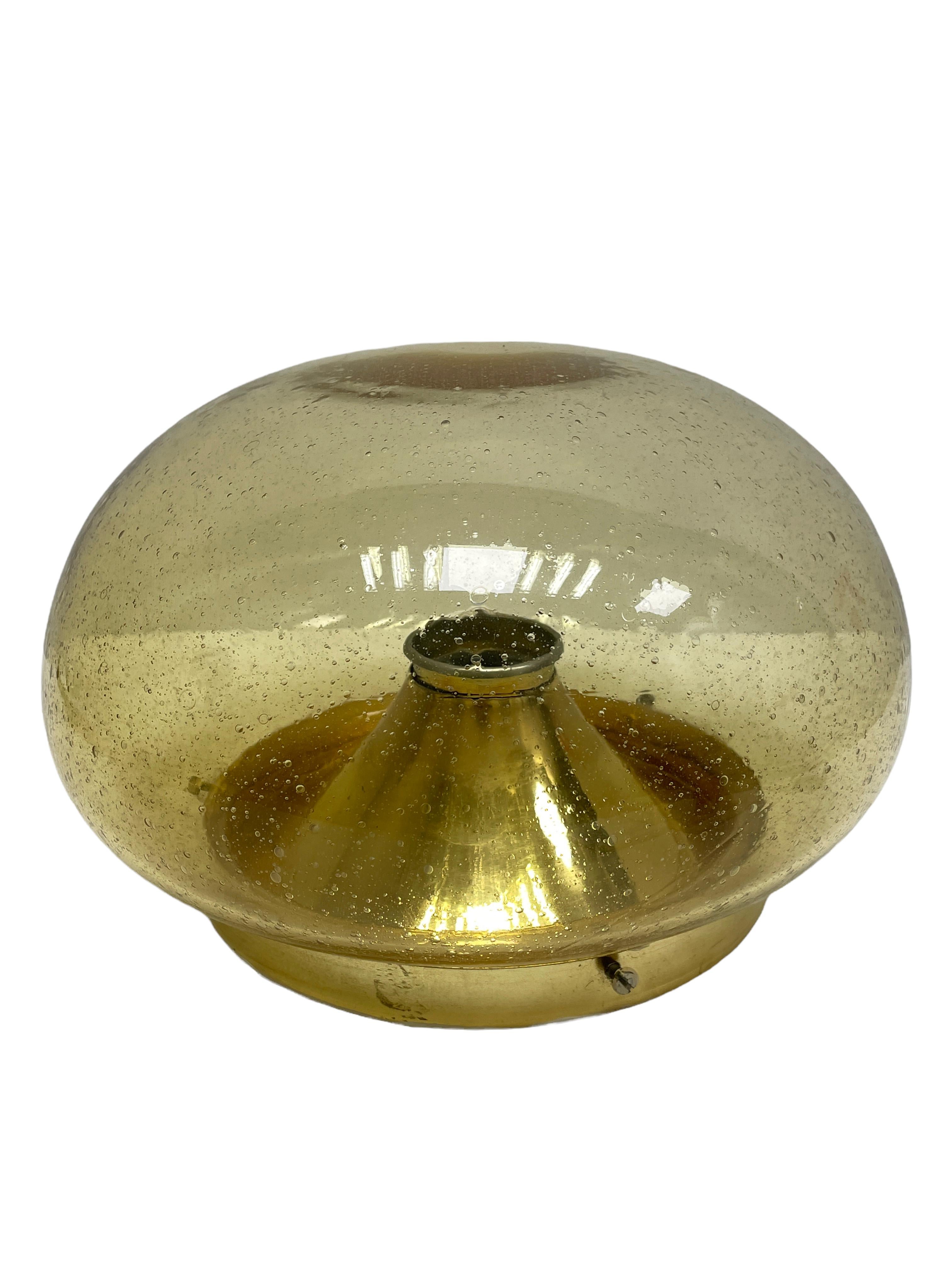 A beautiful flush mount by German manufacturer Glashuette Limburg. The bubble glass element is supported by a polished brass plate with a one light source. Beautiful bubble glass on a metal fixture. The Fixture requires one European E27 / 110 Volt