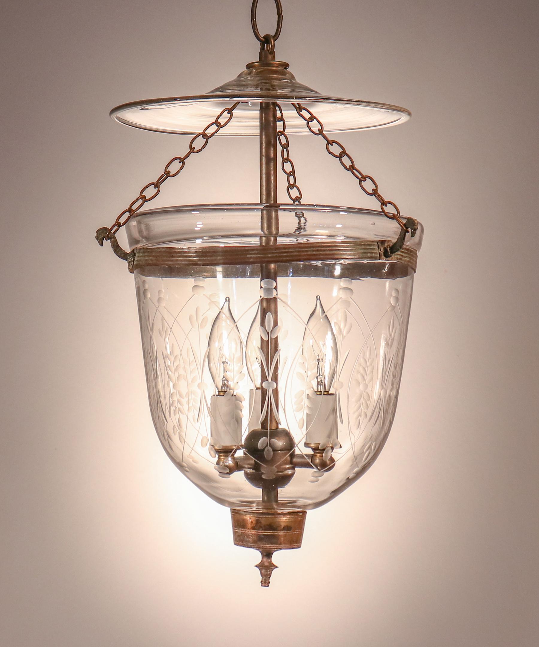 A charming petite English bell jar lantern, circa 1880, with excellent quality hand blown glass and a finely etched wheat motif. The pendant light features all-original brass fittings, including its embossed brass band and candleholder finial base.
