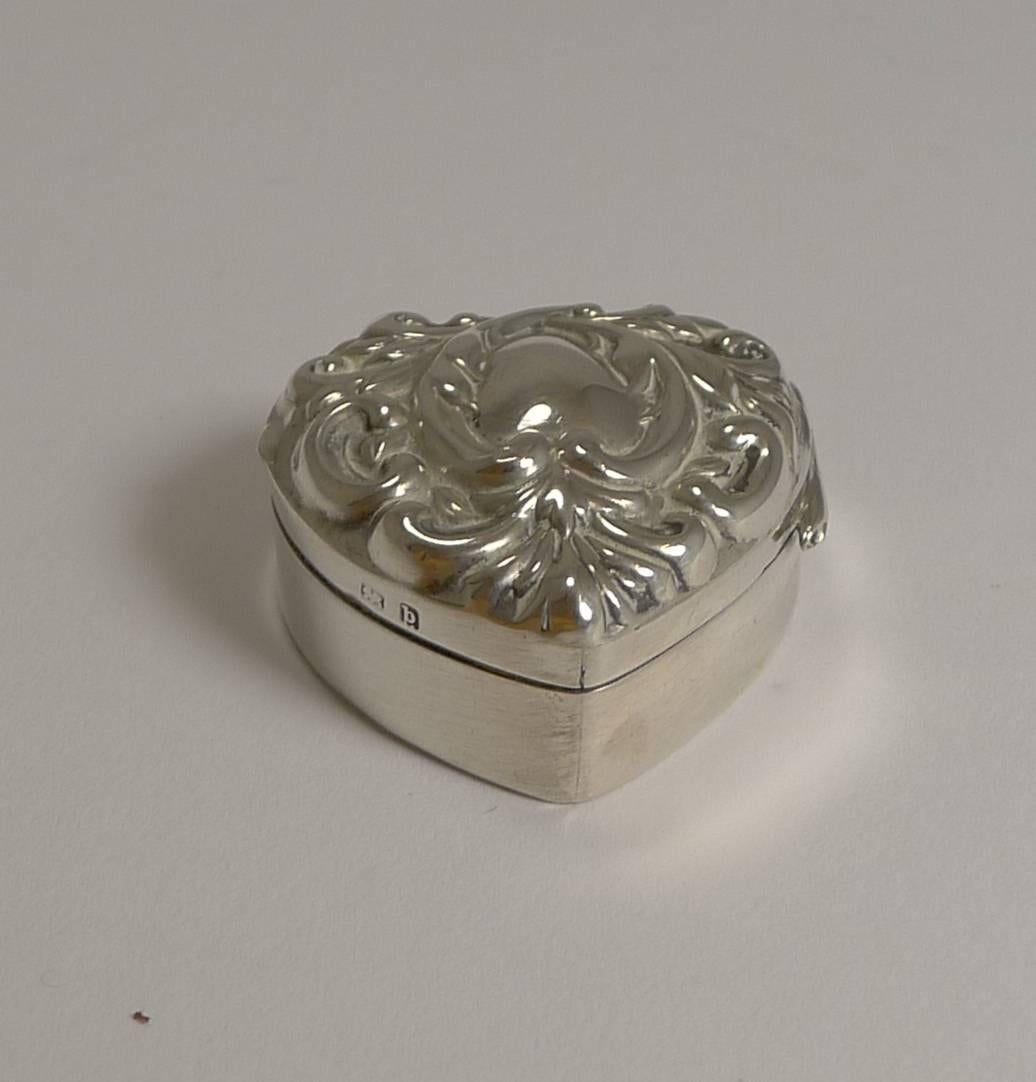 Pretty as a picture with a romantic theme, this small heart shaped pill box is made from English sterling silver hallmarked for Birmingham 1901, a late Victorian / early Edwardian example; the makers mark is also present for Adie and Lovekin