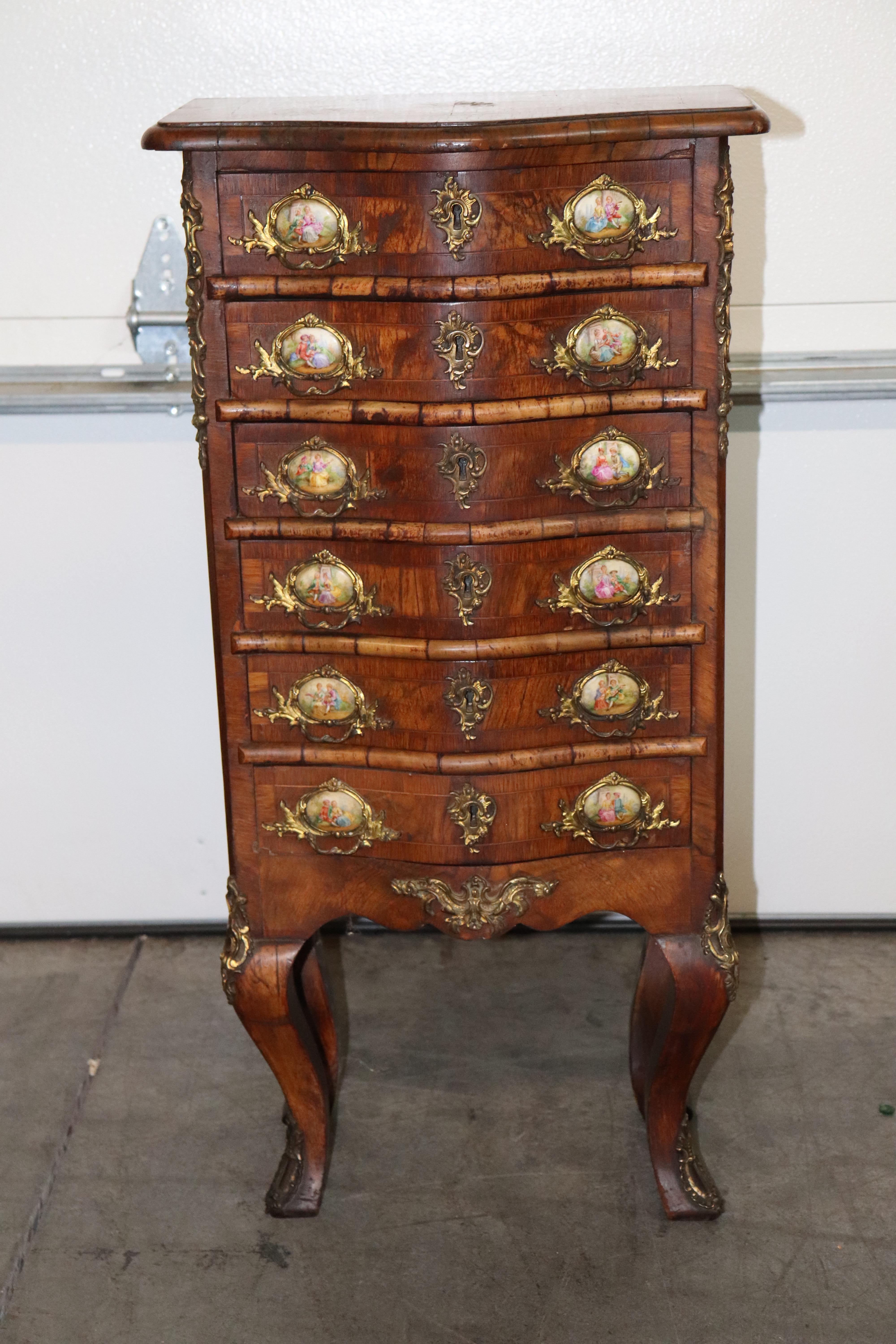 This is a fantastic and rare lingerie chest pf small size. At only 33 inches tall x 17 wide x 11 deep this piece is a small package with a lot of bling. The door handles are set atop porcelain placques in the style of sevres and in good condition.